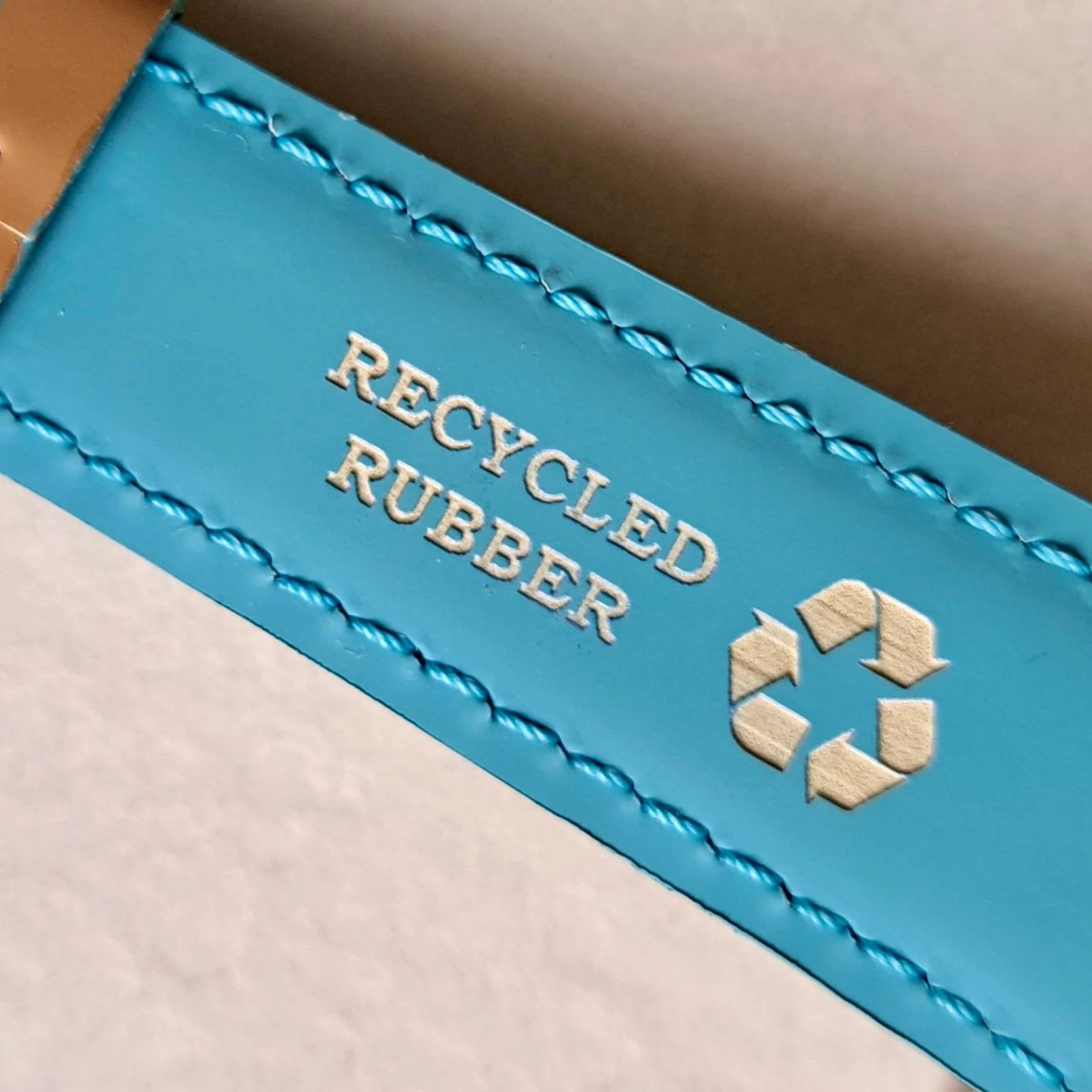 Etichetta di un prodotto riciclato con la scritta 'Recycled Rubber' e il simbolo del riciclo.