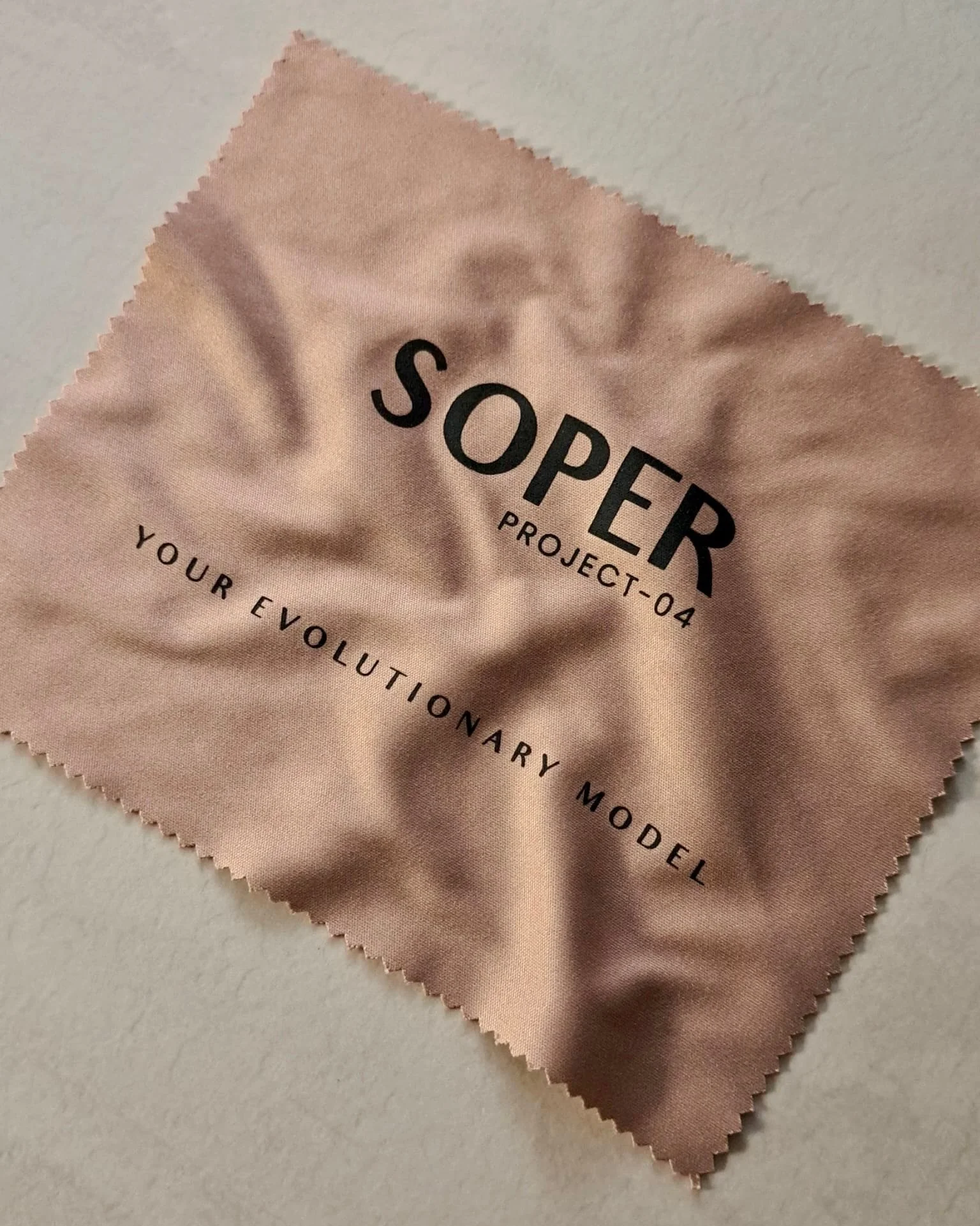 Tessuto con la scritta 'SOPER PROJECT-04 YOUR EVEYOLUTIONARY MODEL' su uno sfondo beige