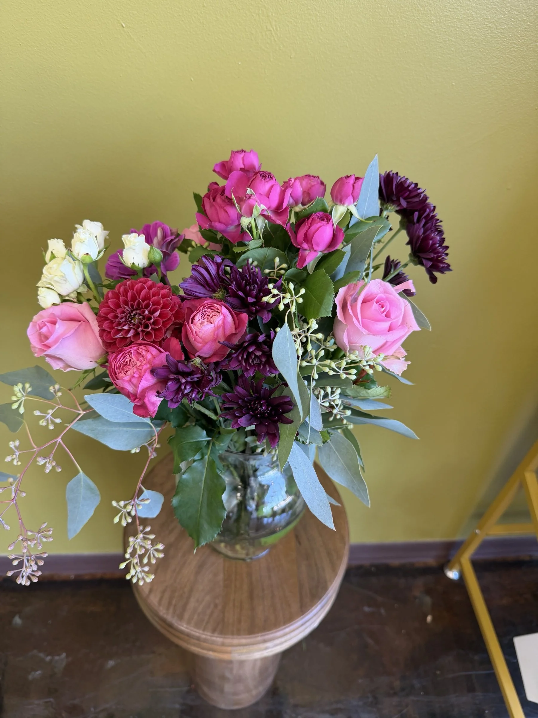 Pink roses, dahlias, purple chrysanthemums and eucalyptus in a vase arrangement at The Strike Team Flowers.