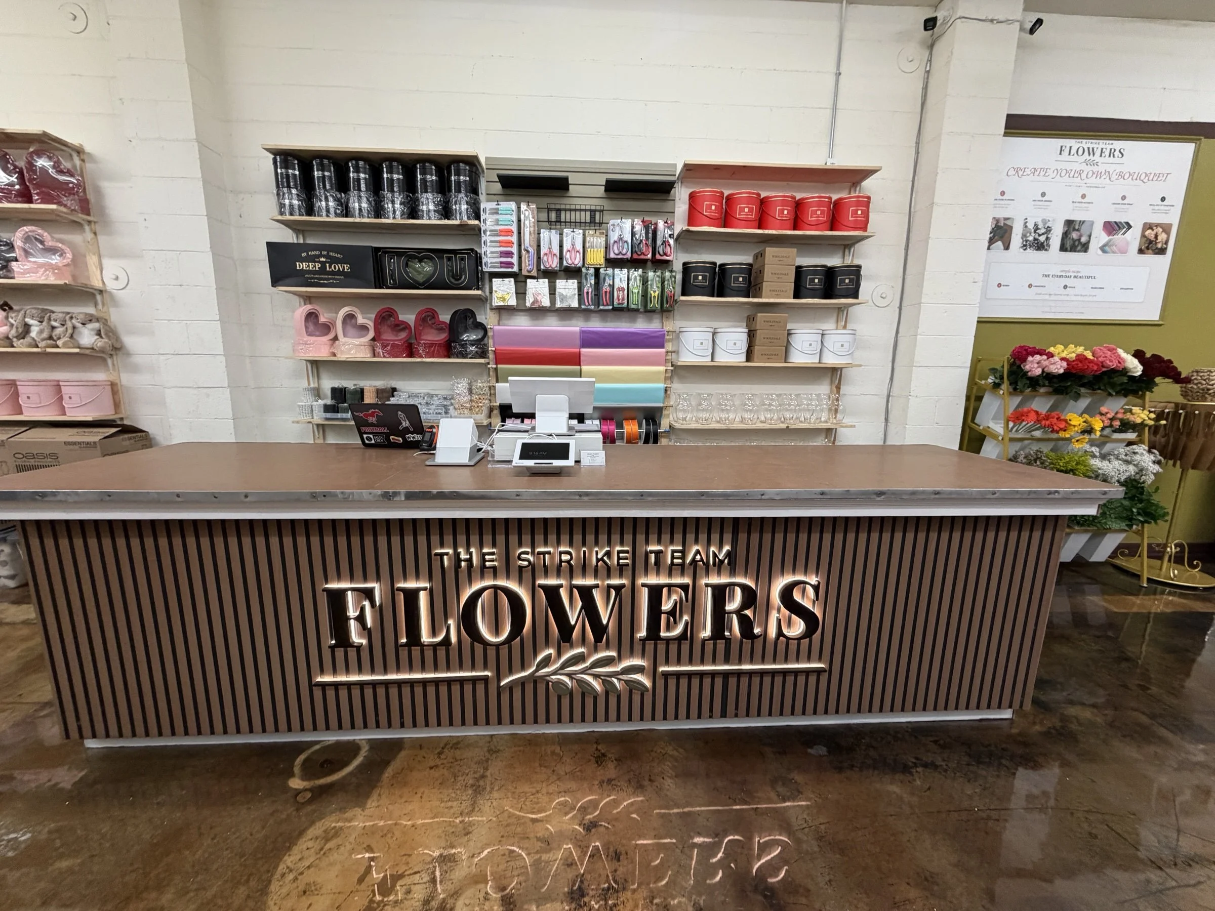 The stocked shop counter, floral supplies and illuminated Flowers sign at The Strike Team Flowers in Concord.