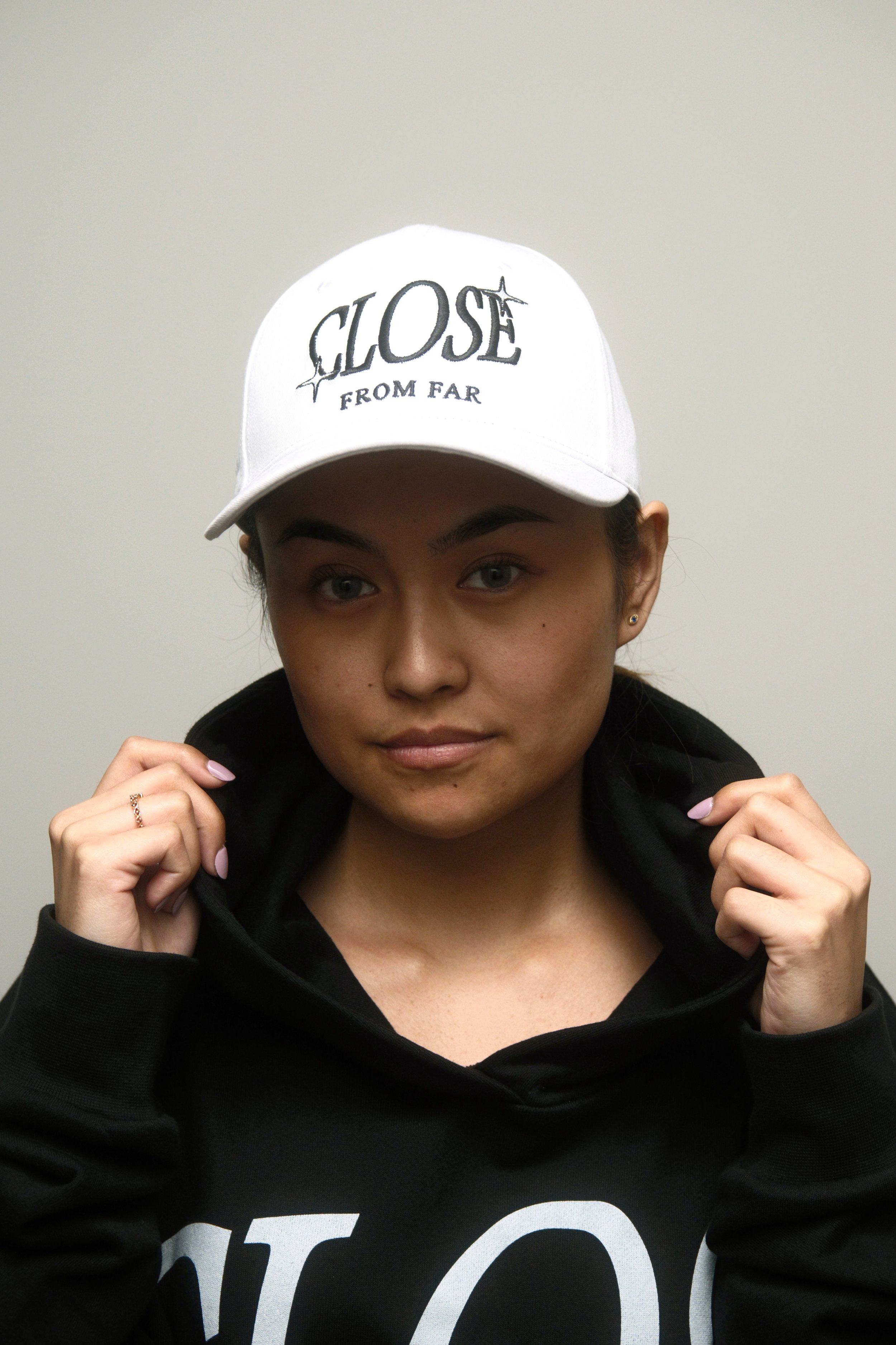 Female Model wearing a Two Stared Close From Far White Cap, Looking straight forward