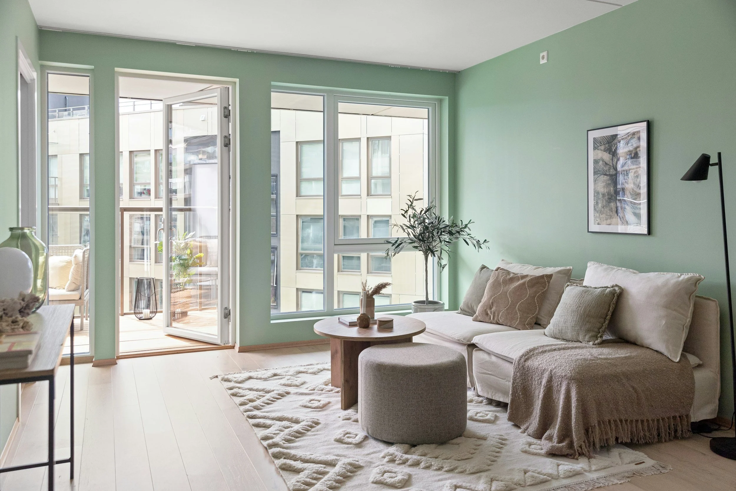 a relaxing uncluttered living space for the autistic community. Pastel greens, natural sofa and rug, and lots of natural light. Neurodivergent living.
