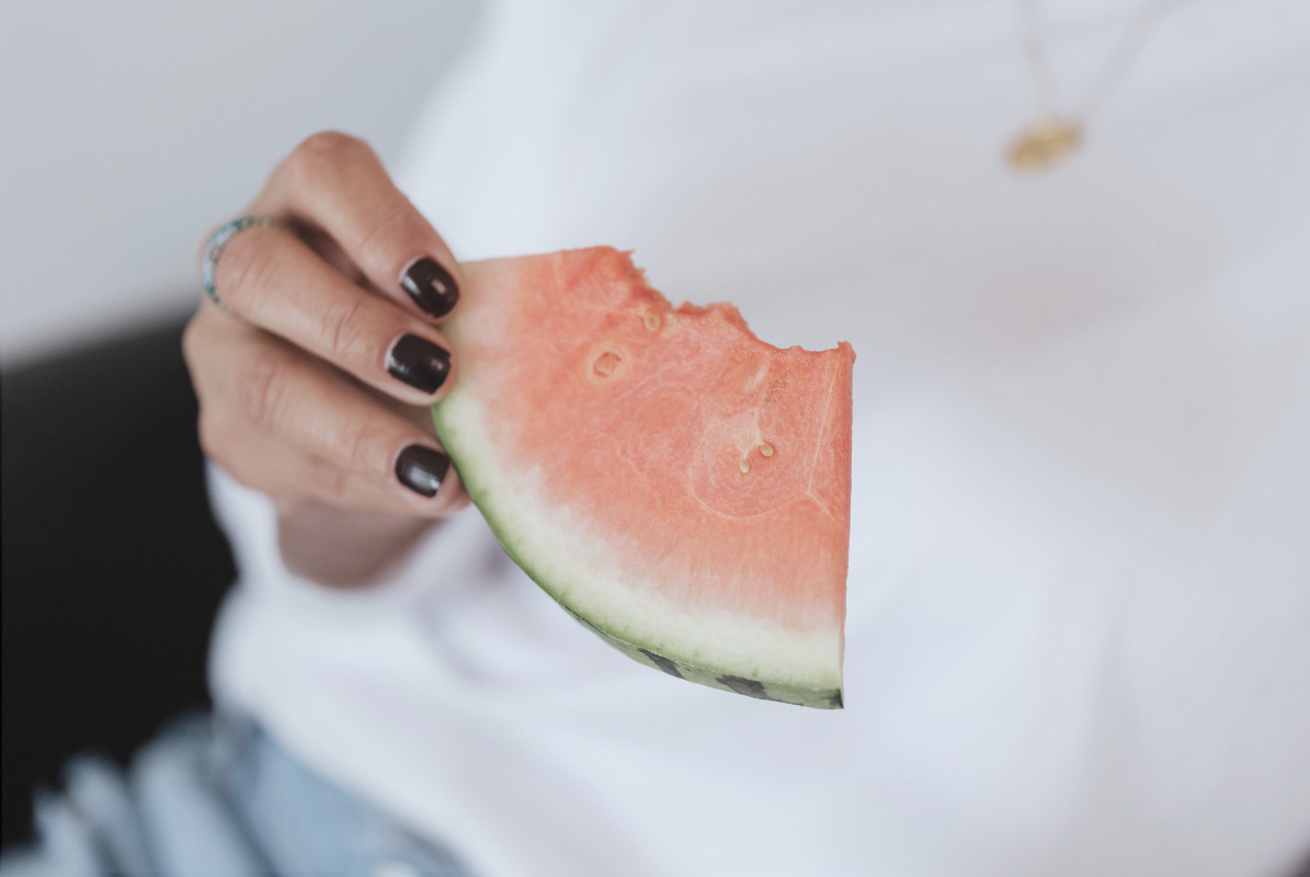 A person holding a slice of watermelon.