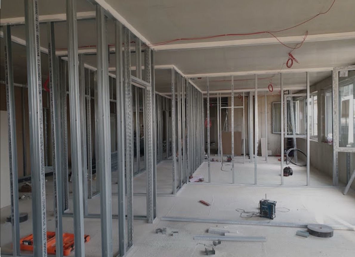 Innenansicht einer Baustelle mit Metallrahmen für Trennwände in einem Gebäude.