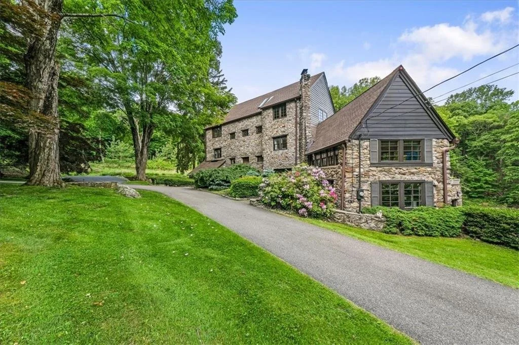 Stone house with a sloped roof surrounded by trees and landscaping