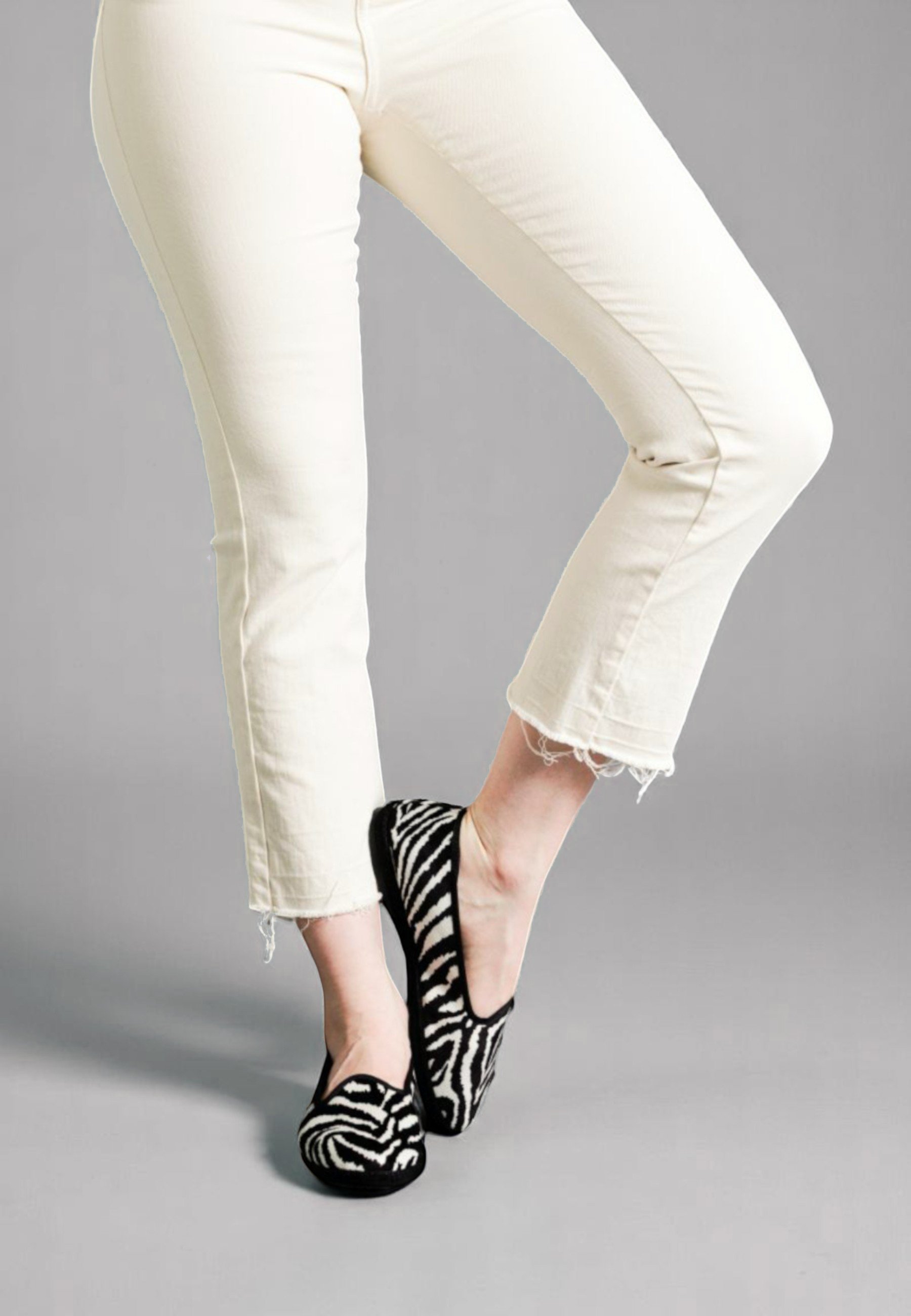 One foot lifted, Zebra print velvet Gioia slippers styled with playful poise
