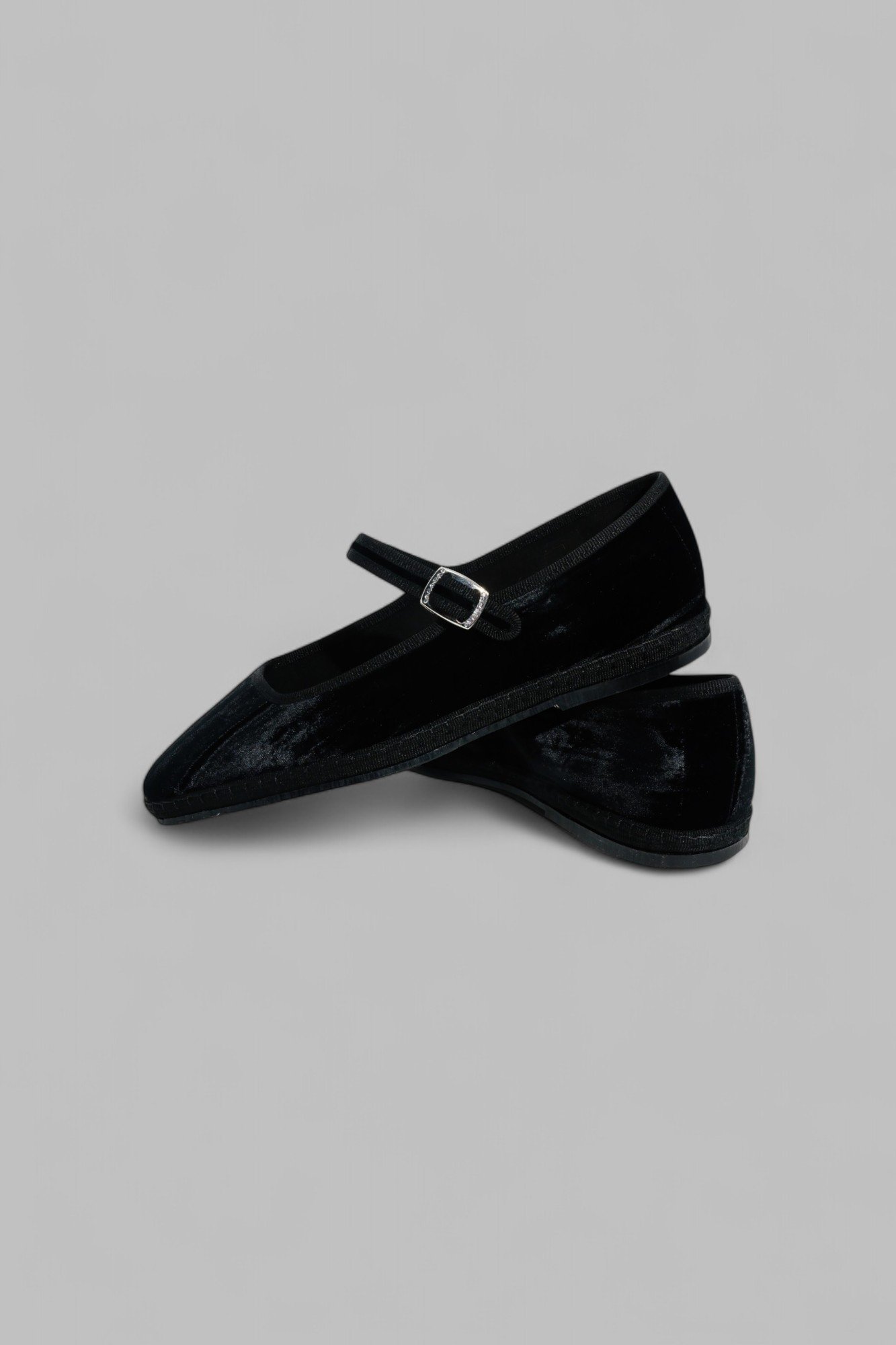 Pair of black velvet Mary Janes overlapped, one slightly lifted