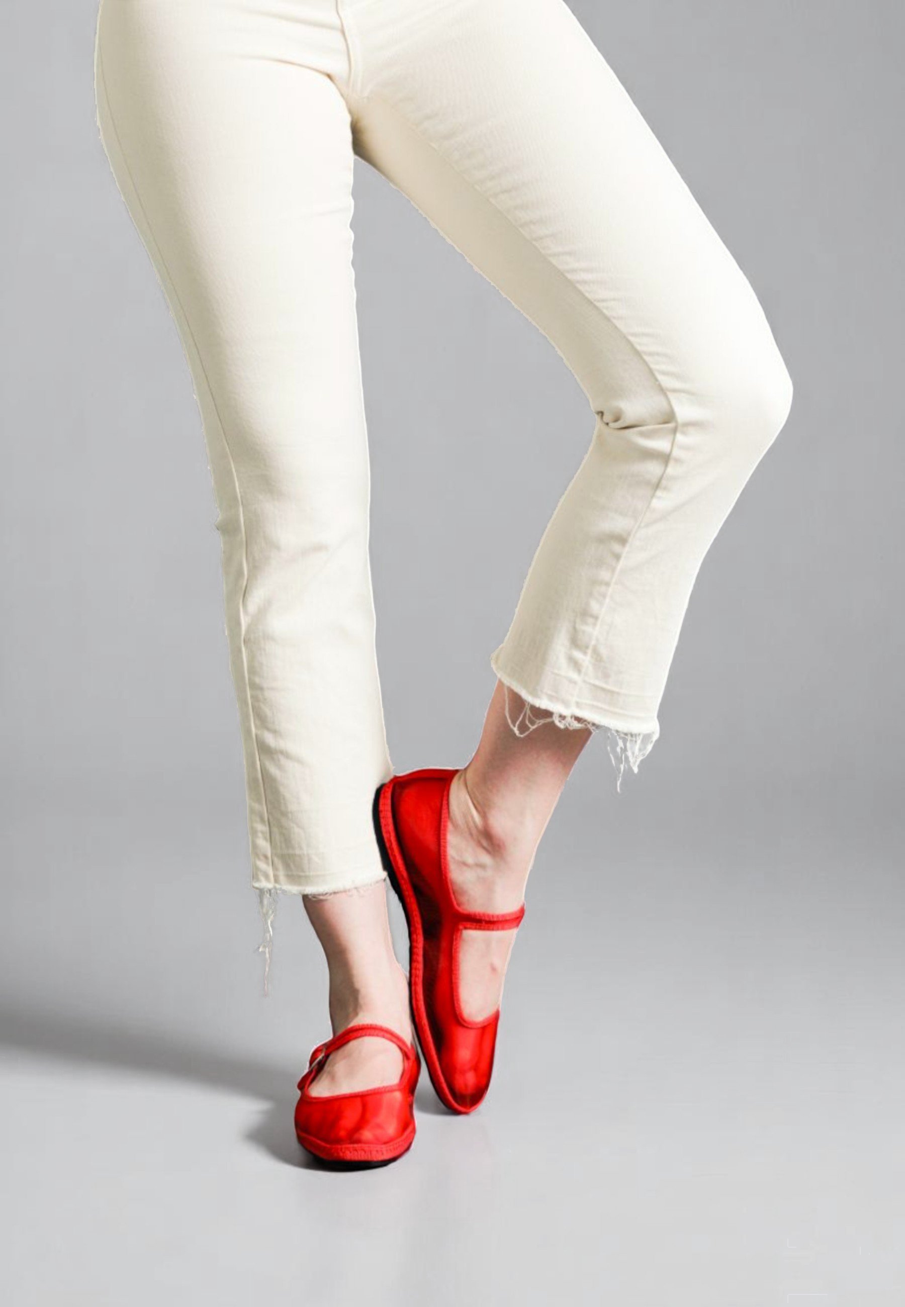 Playful lifted-foot stance in satin Flame Aria flats, bold against pale denim