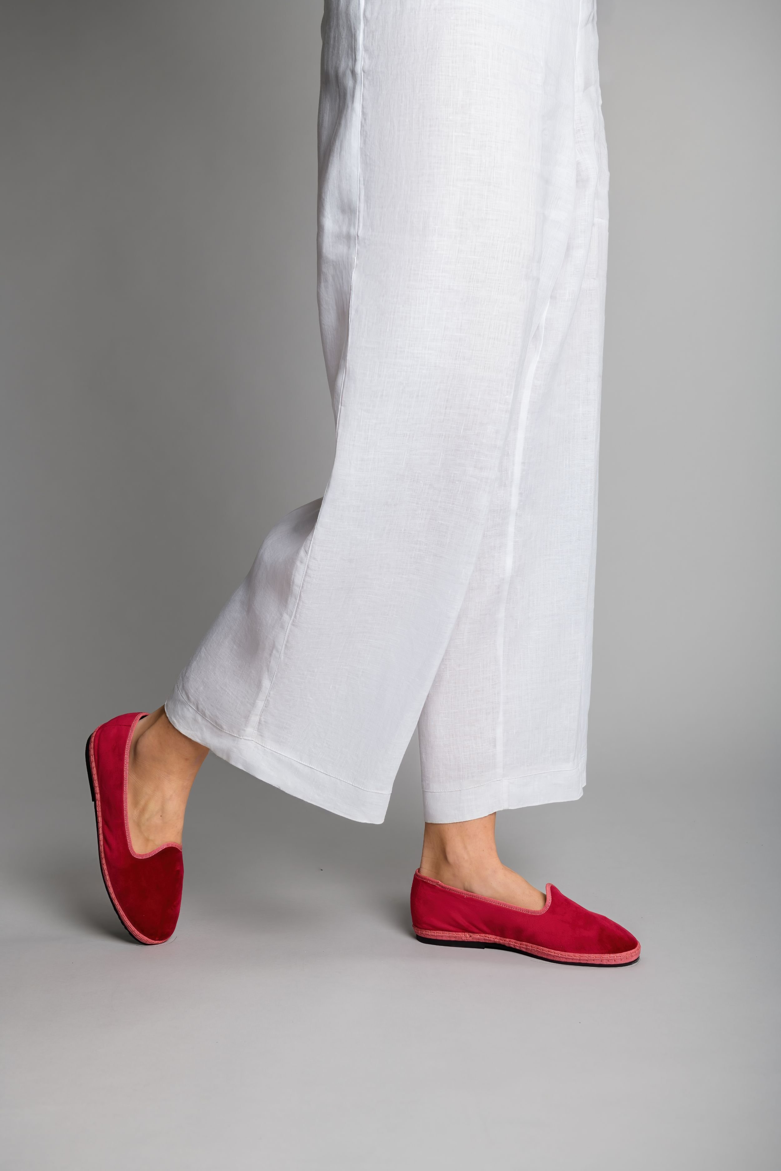 Side step of model wearing Lipstick Rose velvet slippers with wide-leg trousers