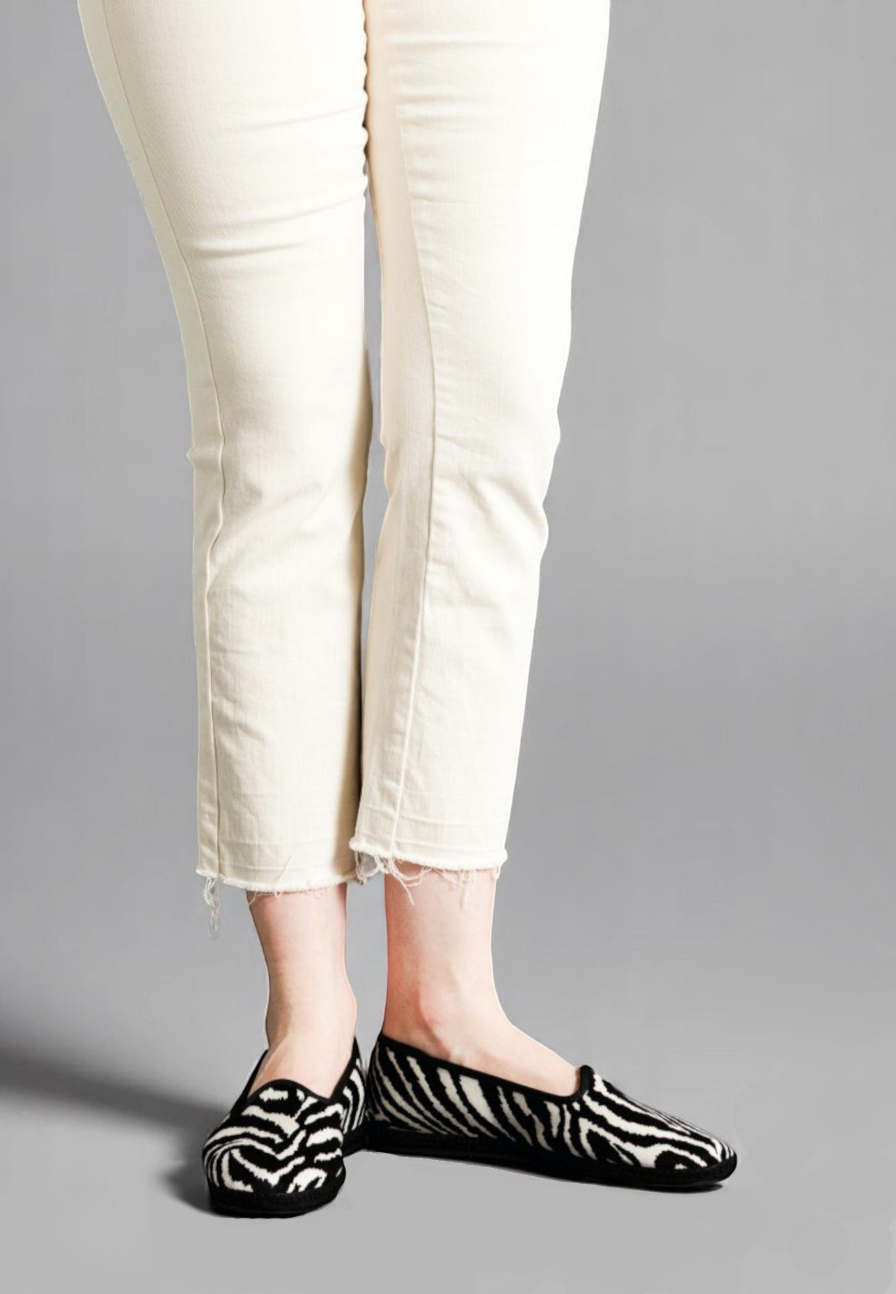 Front view of model wearing Gioia italian slippers in velvet Zebra pattern, with frayed ivory denim