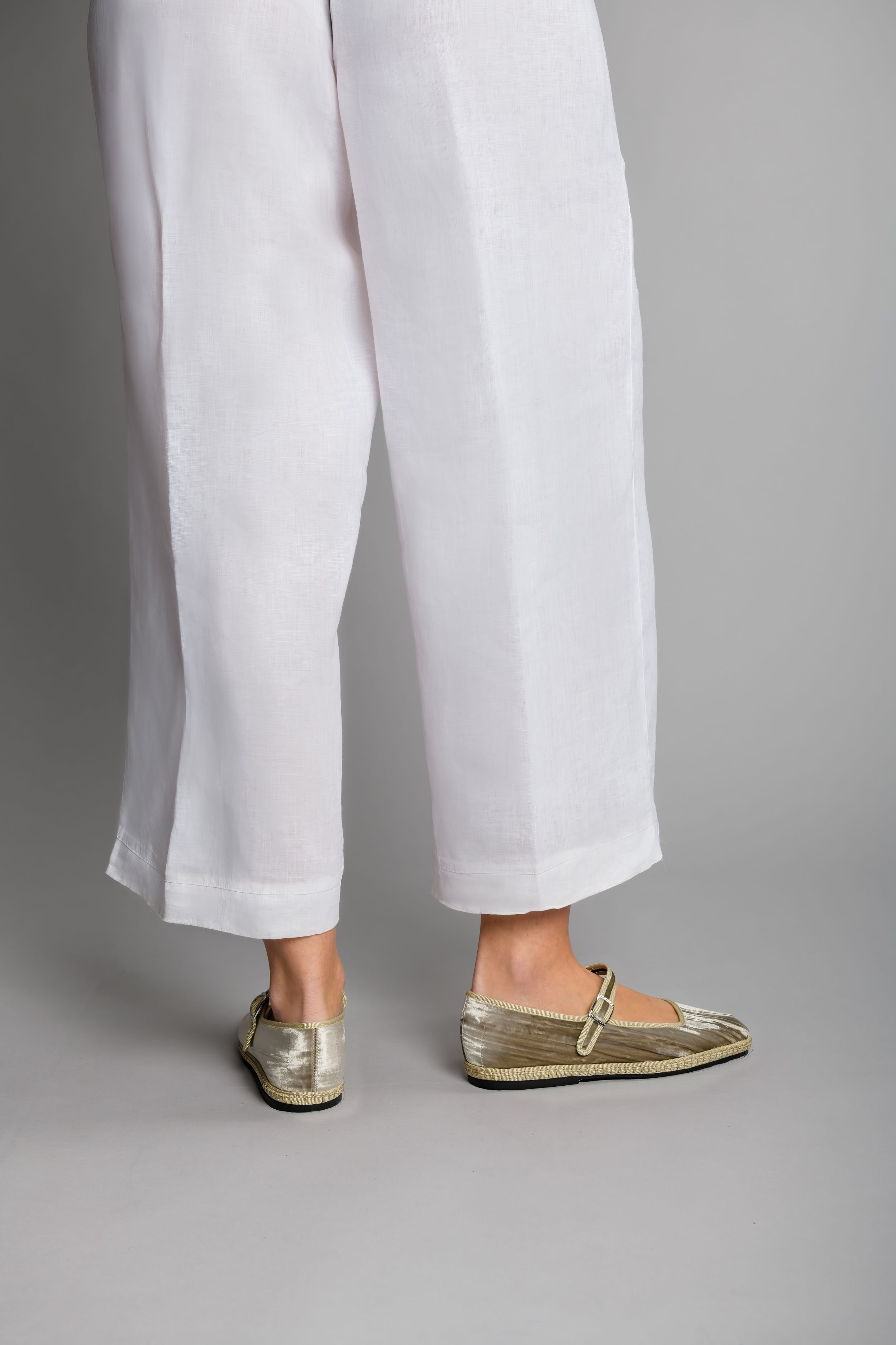 Back view of model wearing Champagne velvet Mary Jane flats with white linen pants