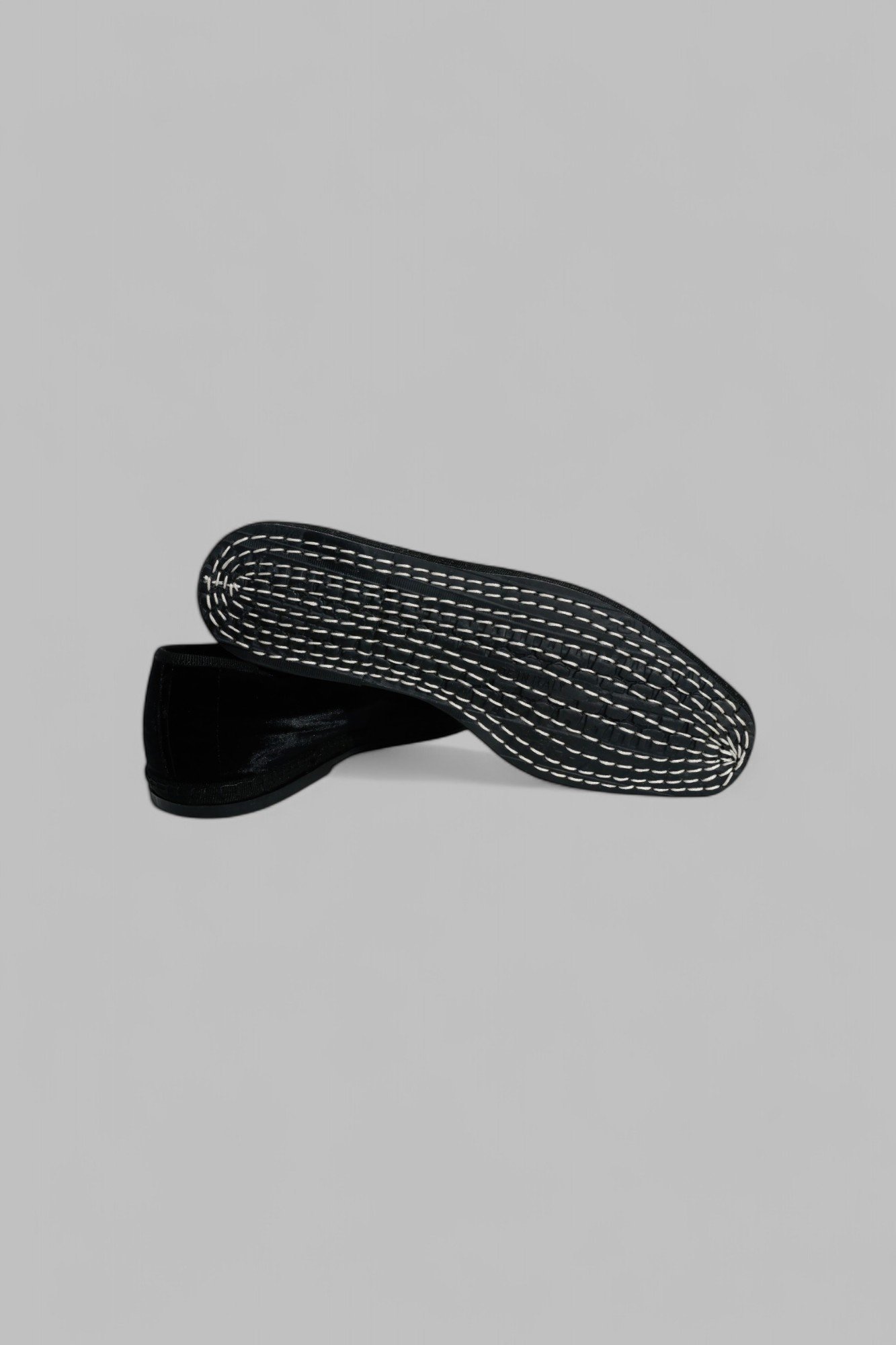 Stacked view of shoe pair, showing stitched rubber sole