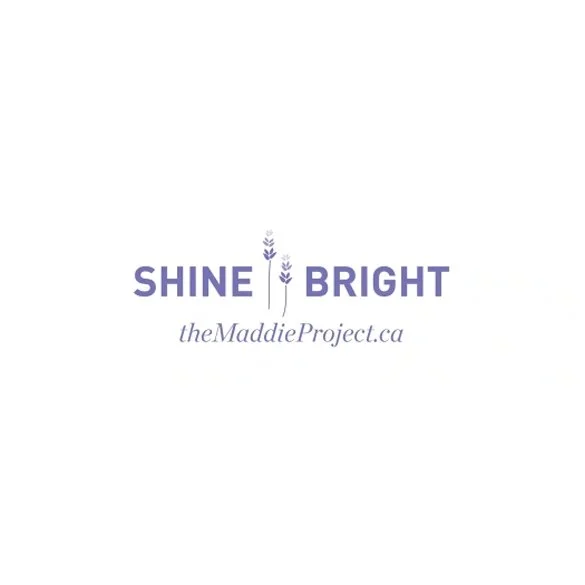 Logo with the words "SHINE BRIGHT" in purple, with stylized lavender flowers between the words, and the website 'theMaddieProject.ca' underneath in gray.