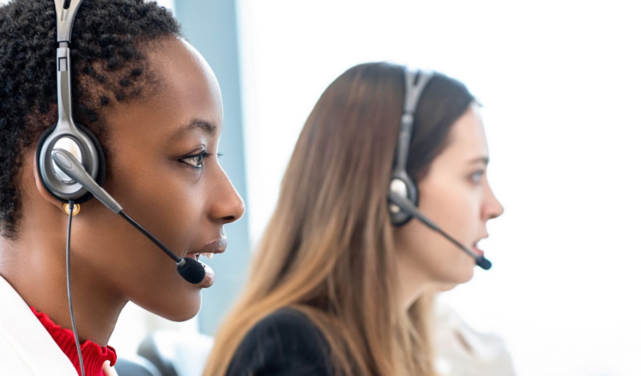 Two women wearing headsets working in a call center, focusing on their tasks.