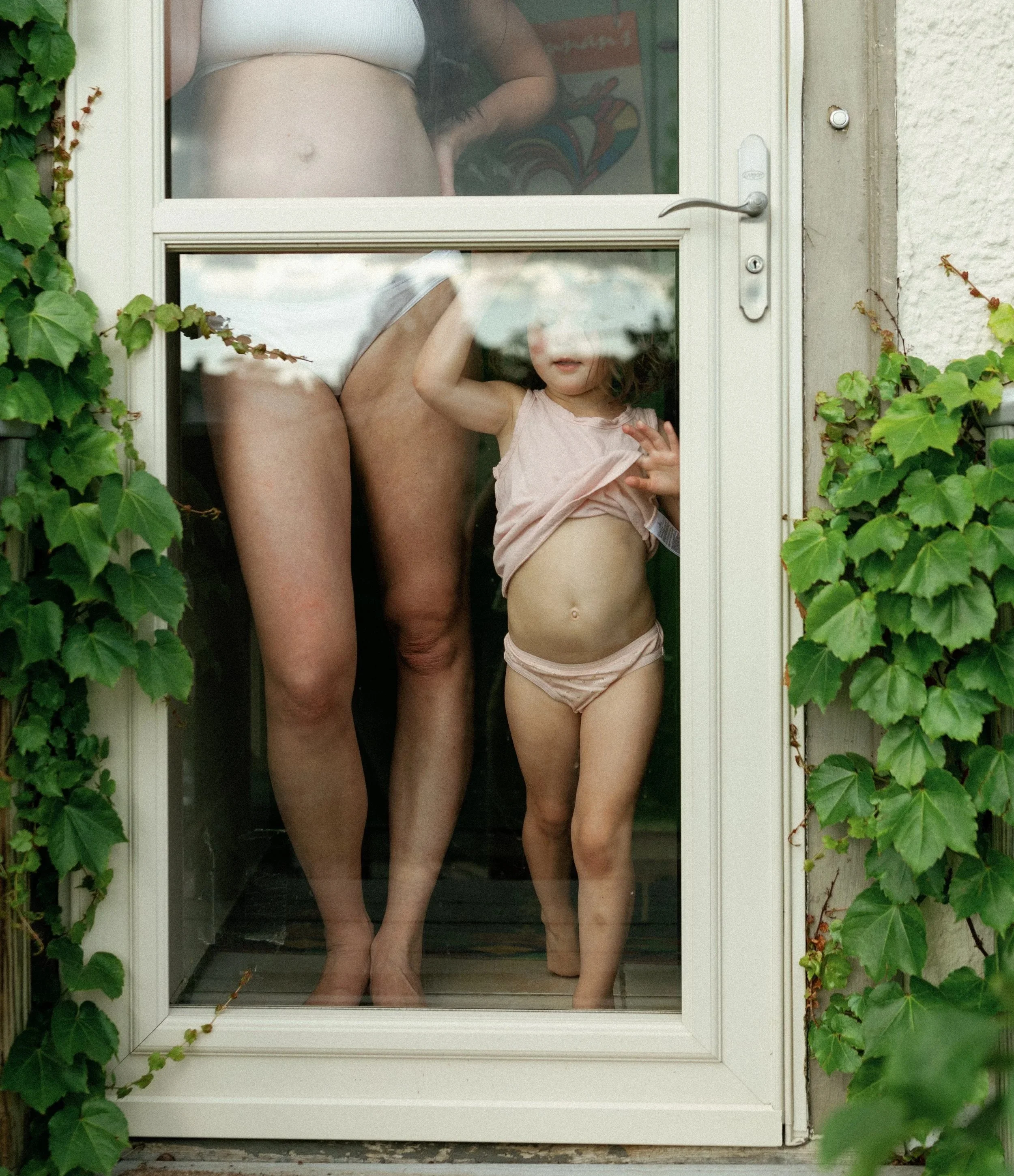 pregnant mother and daughter looking through glass