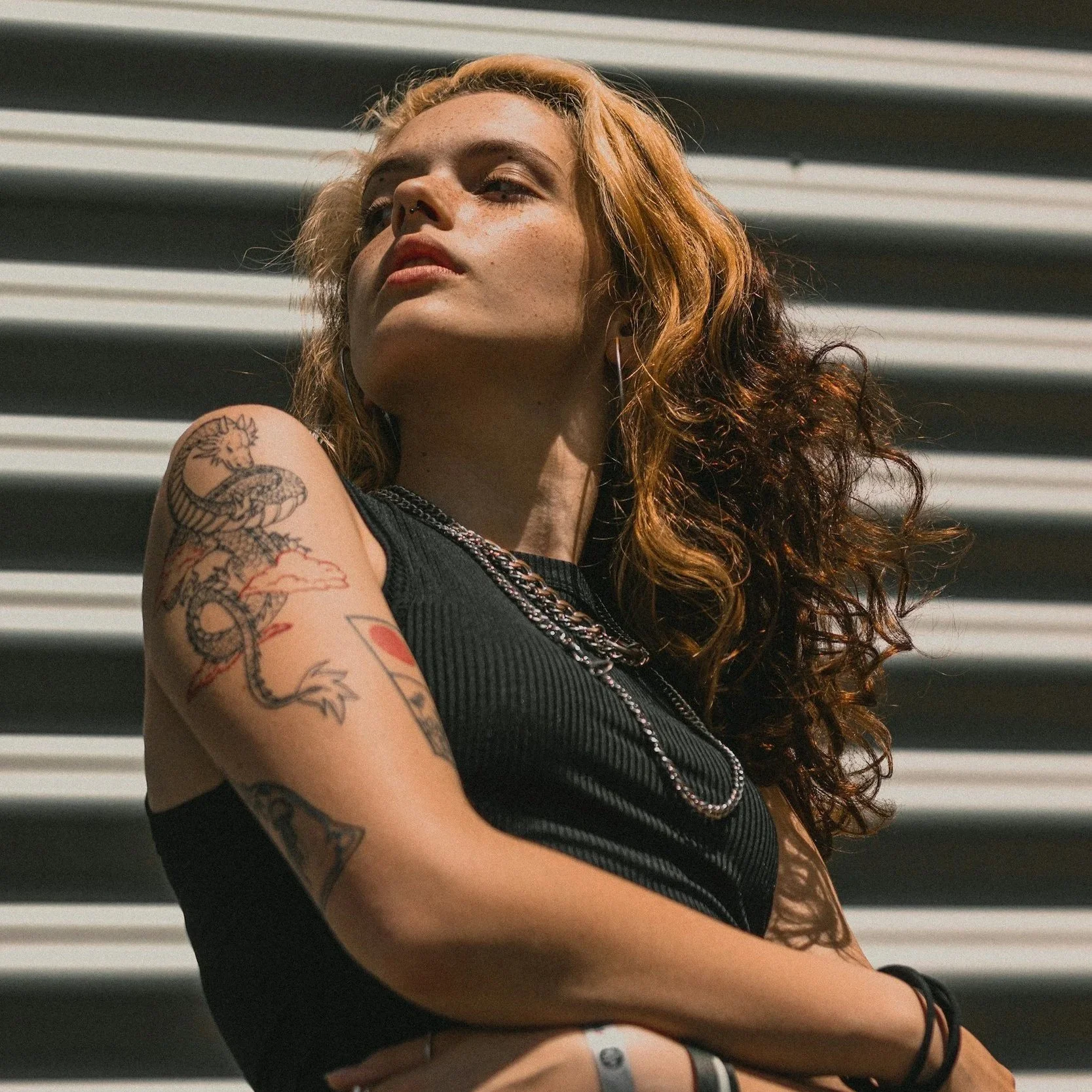 A woman with blonde and red wavy hair posing against a metal background.