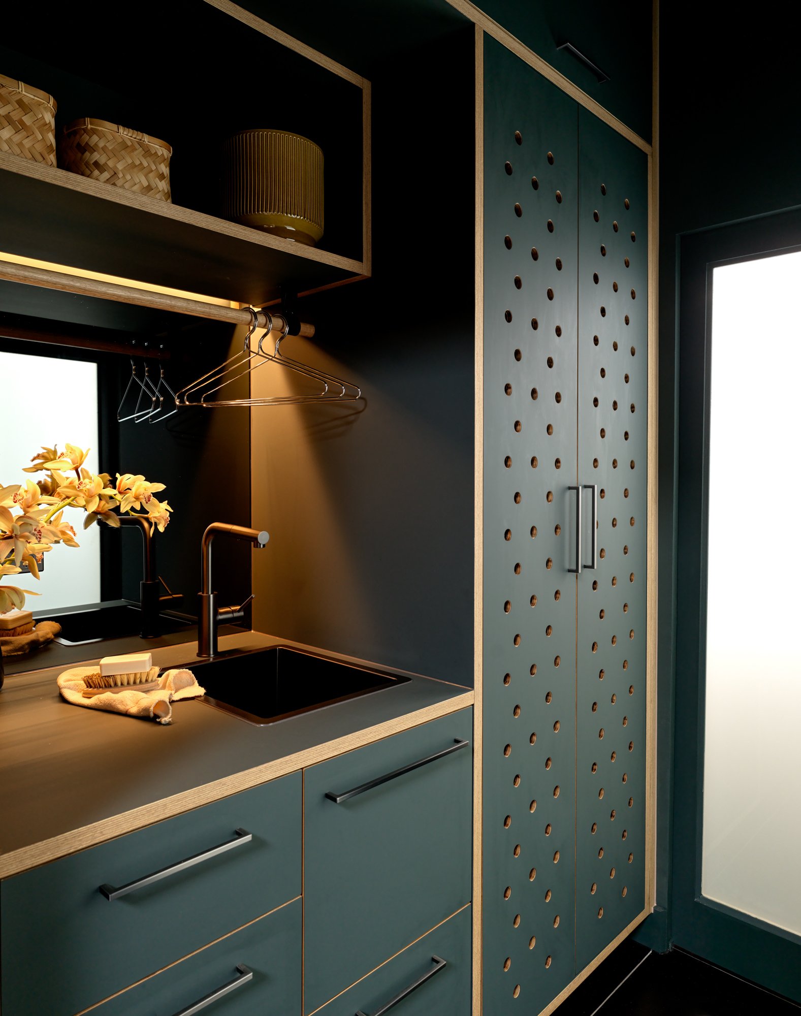 Brunswick Laundry showing the compact sink area, hanging rail and full-height perforated green cabinetry.