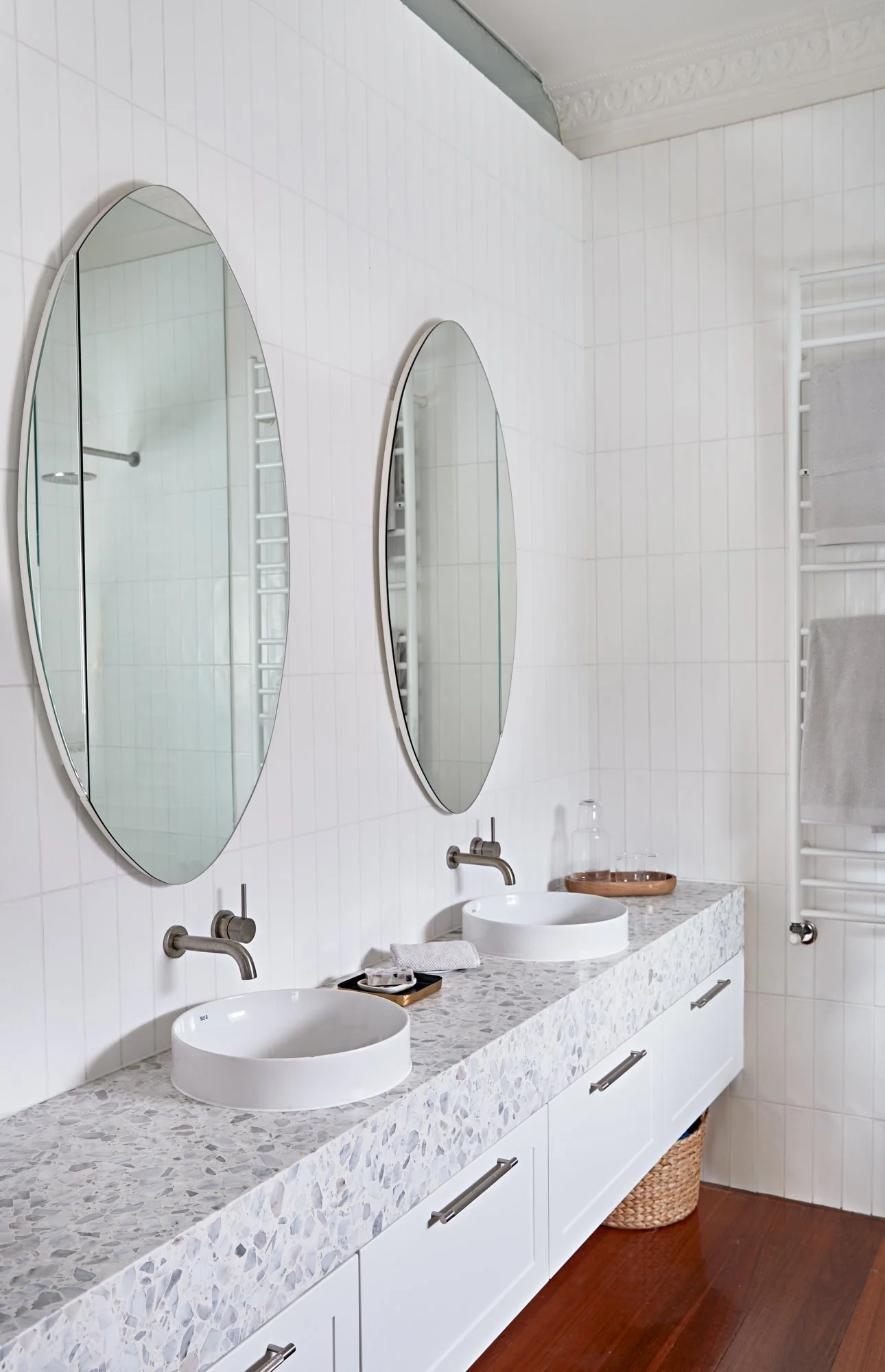 Ensuite with double vanity, round mirrors, white tiled walls and terrazzo benchtop at Adella Court, Elwood.