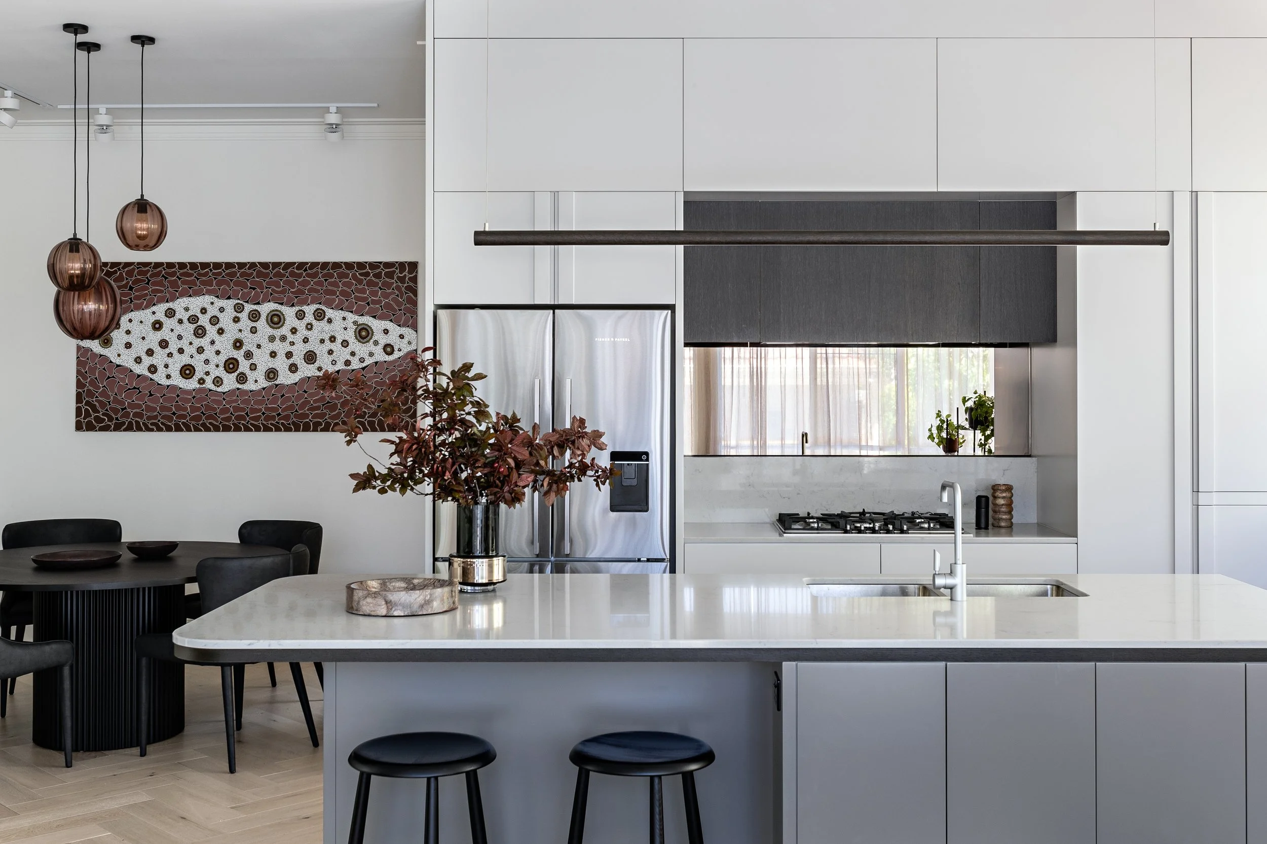 Open-plan kitchen and dining area with island bench and integrated cabinetry at Brighton East House.