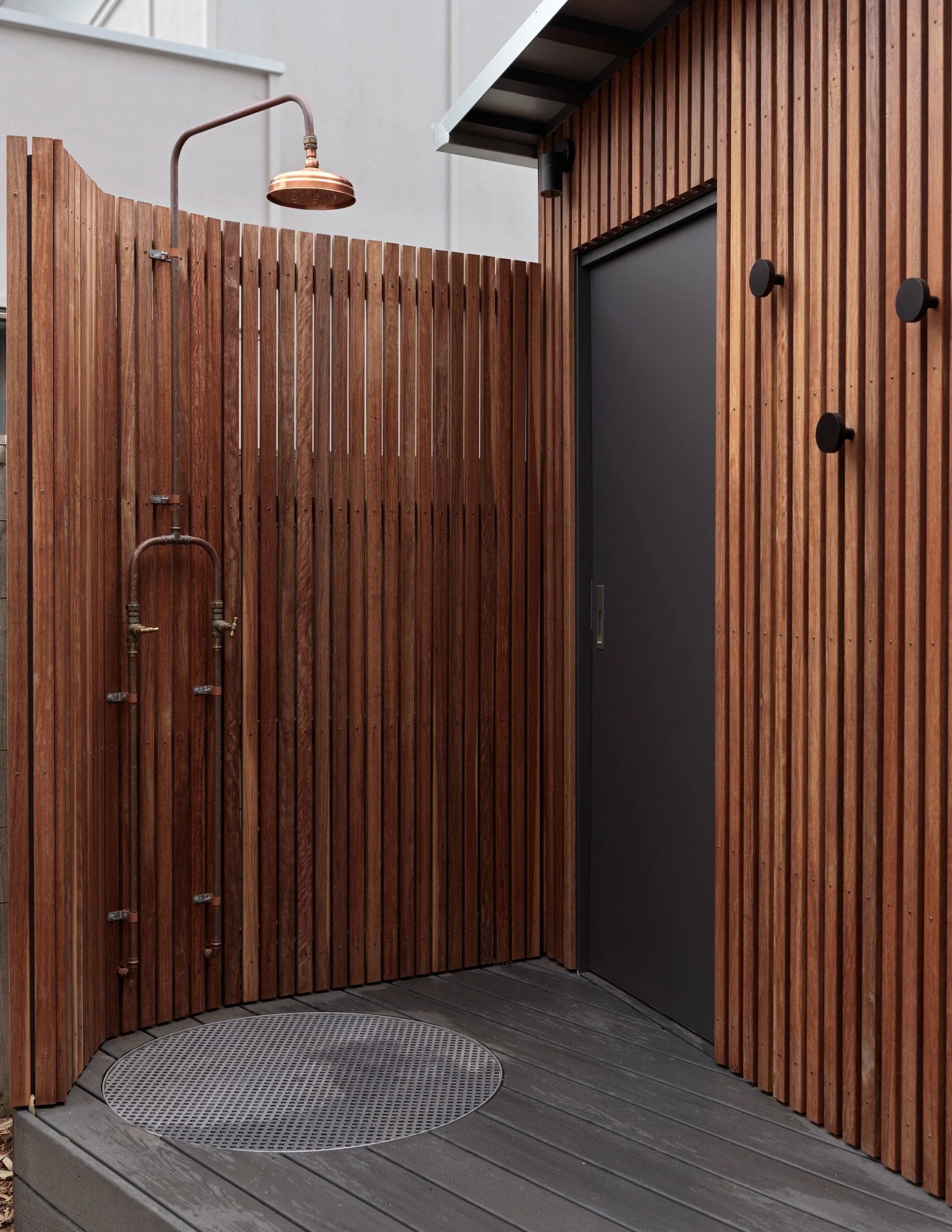 Outdoor shower at Cottesloe Retreat enclosed by vertical timber screening beside the timber-clad exterior.