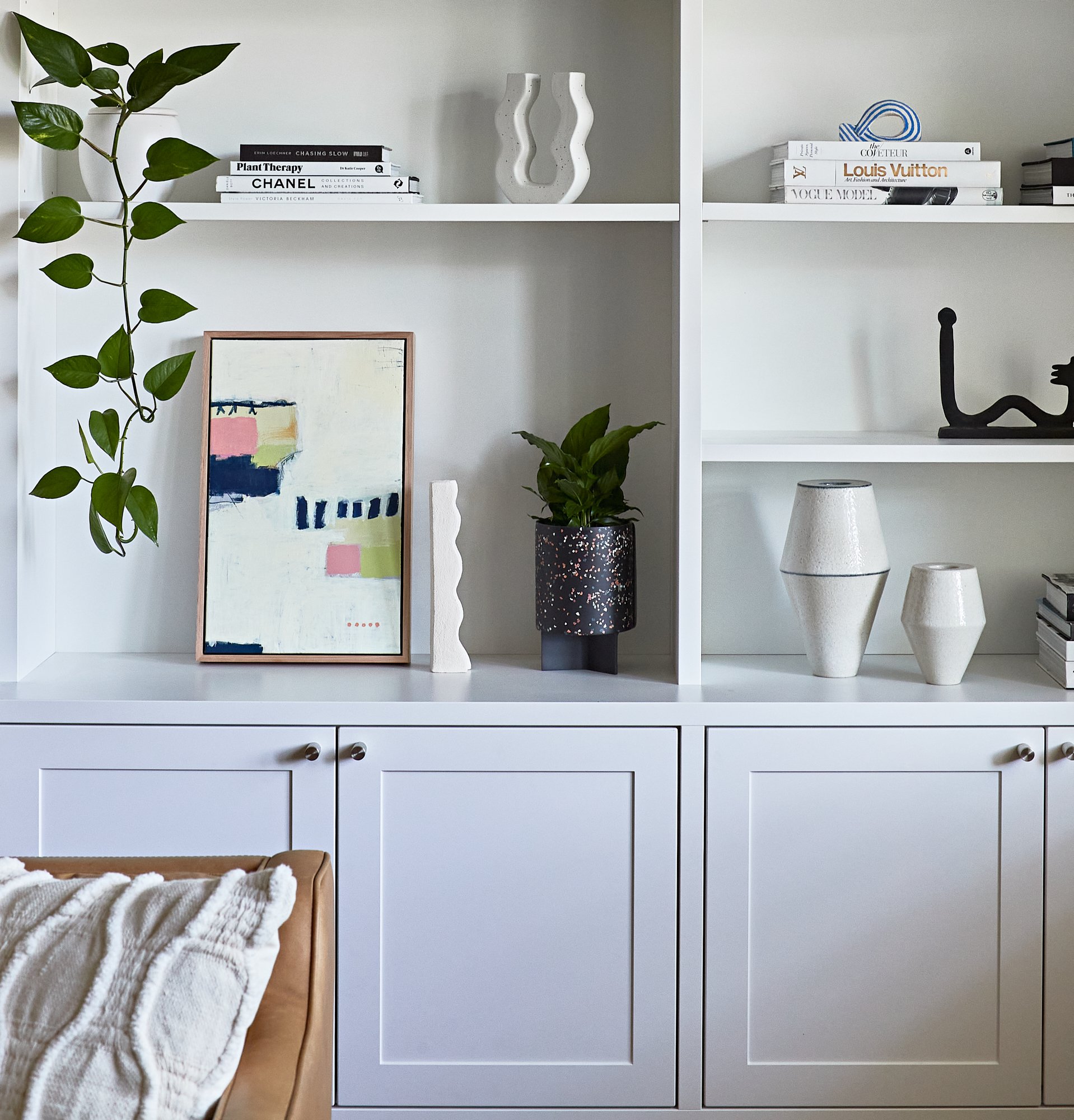 Detail of custom built-in living room shelving displaying books, artwork, plants and objects at Adella Court, Elwood.