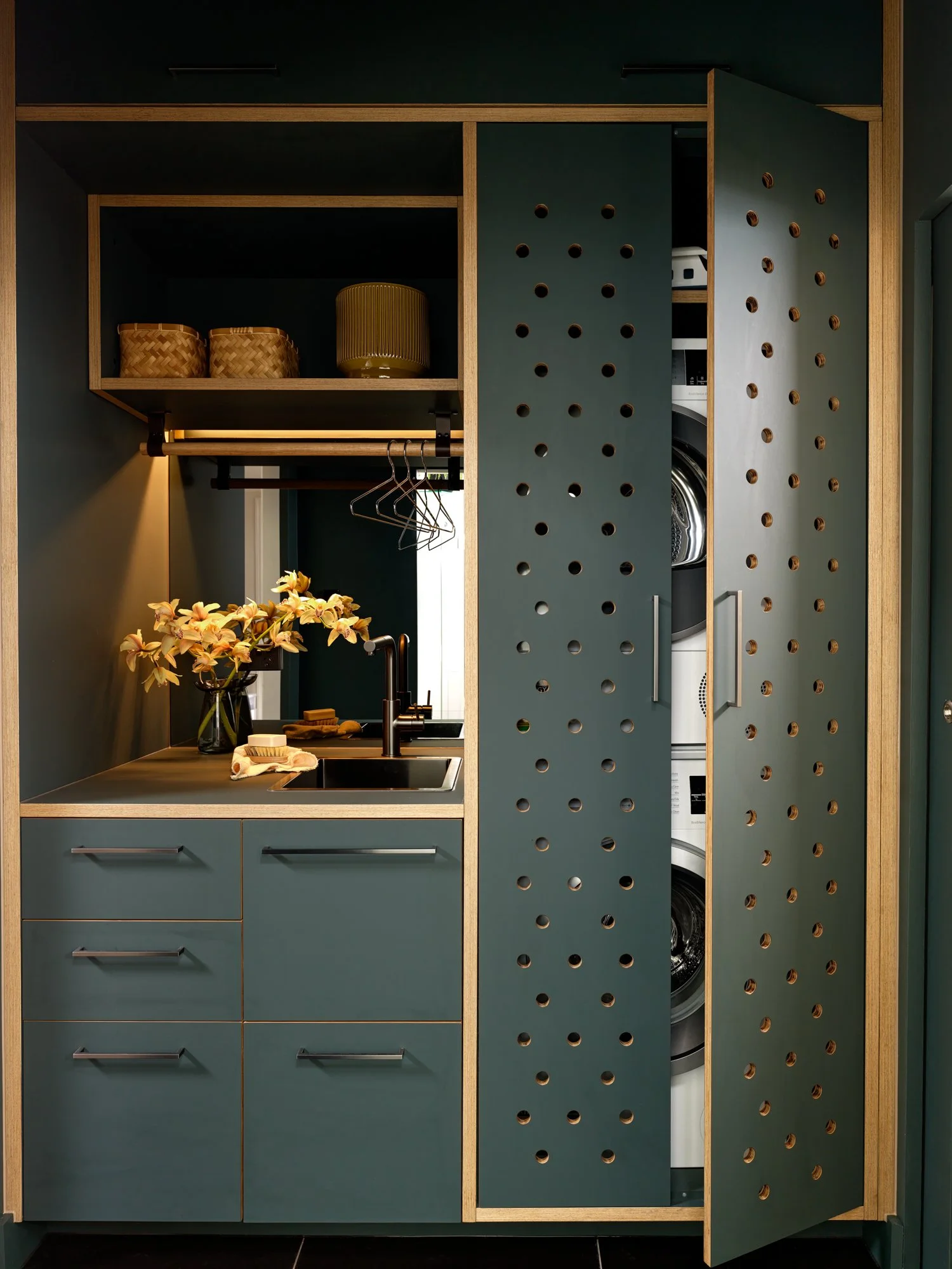 Brunswick Laundry with perforated cabinet doors open to reveal the concealed stacked washing machine and dryer.