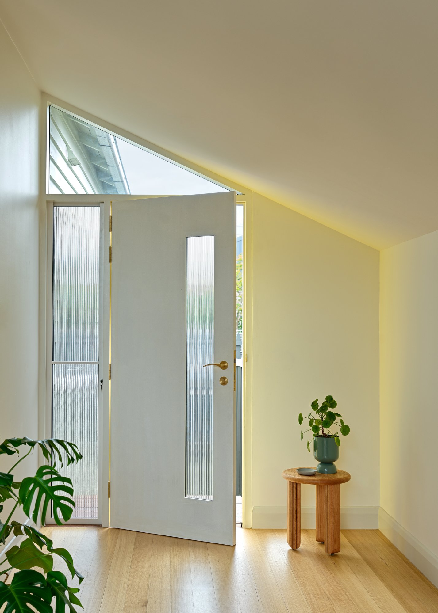 Front entrance to Northcote Extension with an angled ceiling, glazed front door and natural timber flooring.