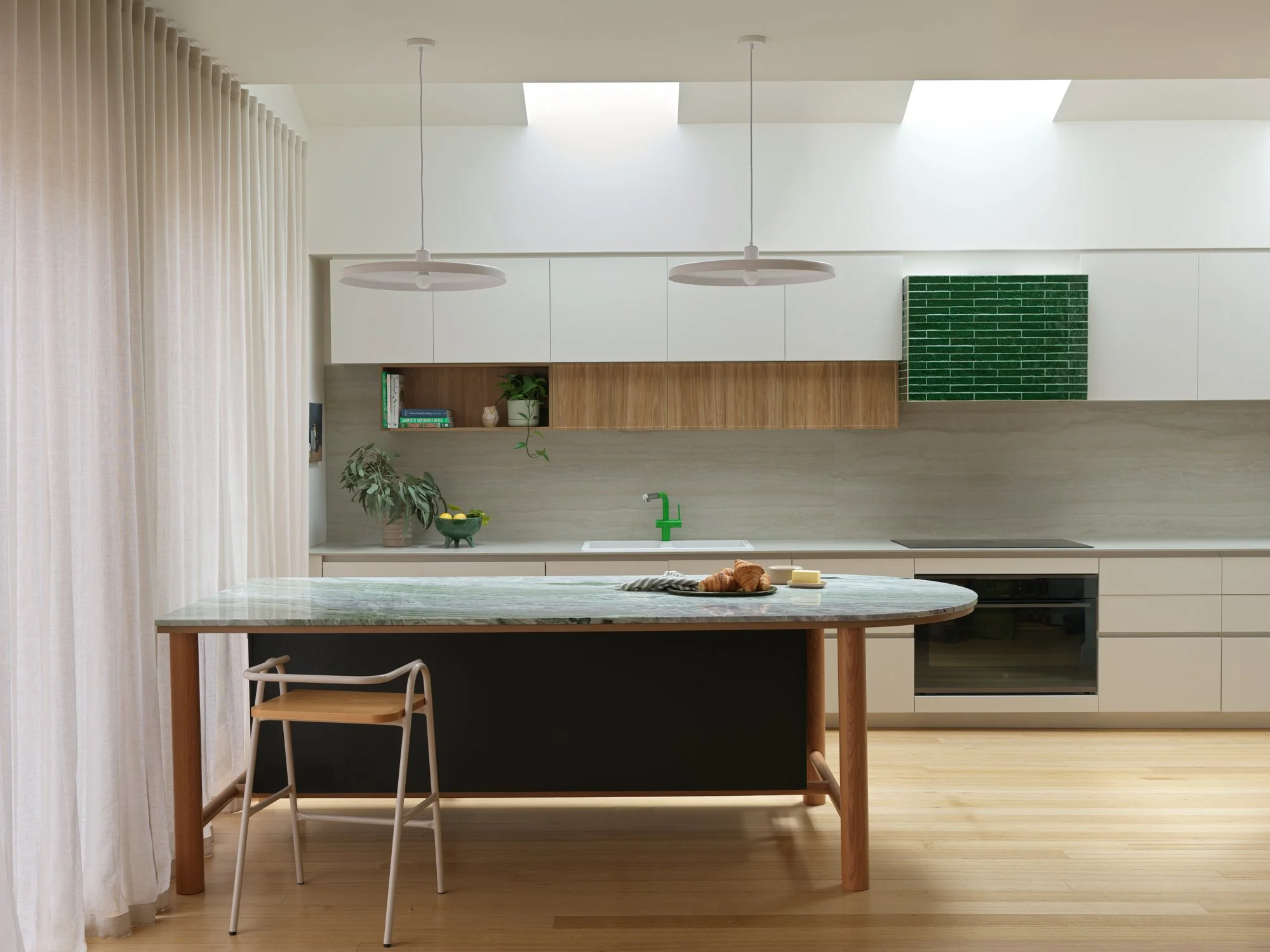 Northcote Extension kitchen with a large stone island, timber detailing, white cabinetry and skylights bringing natural light into the space.