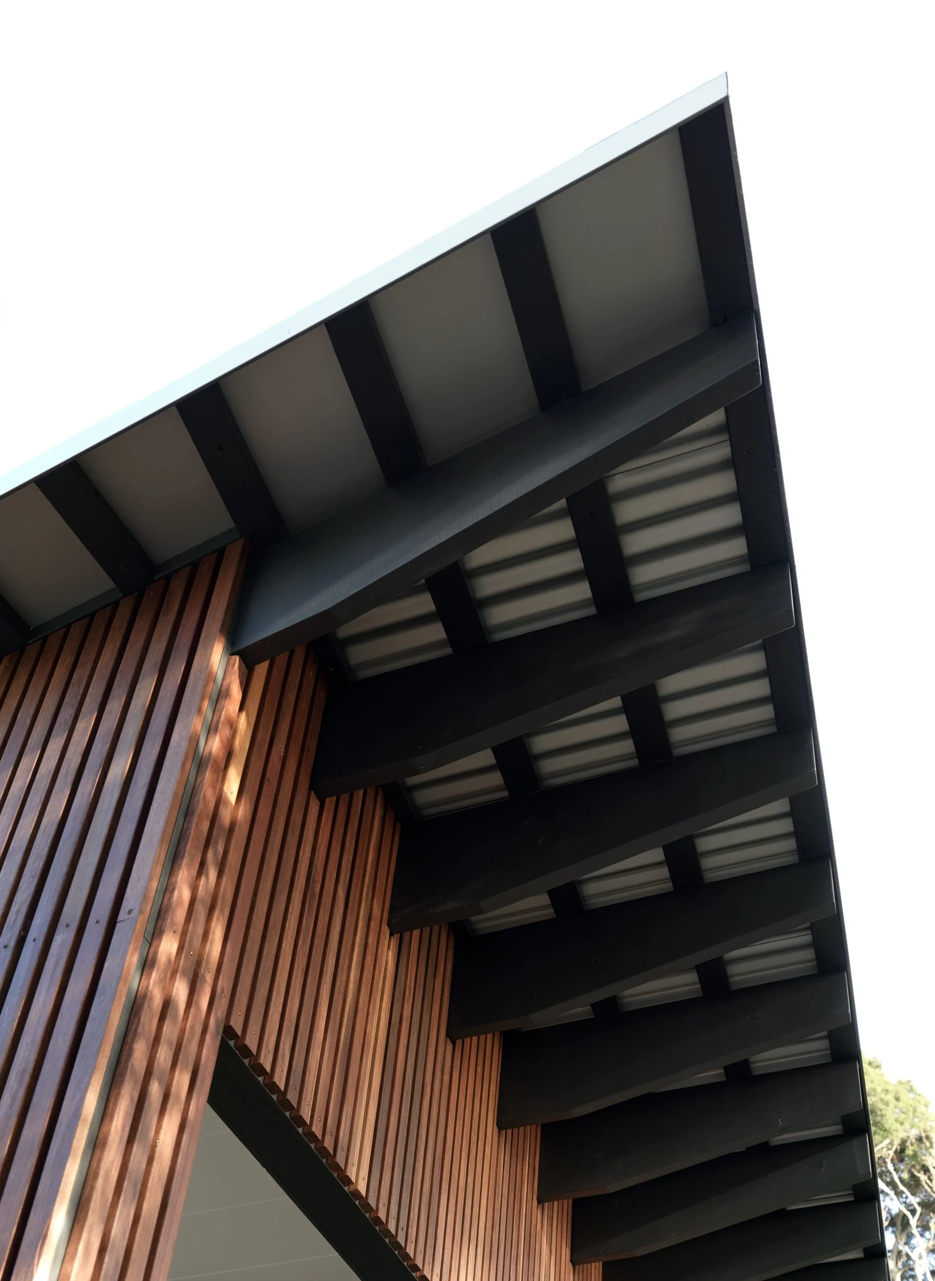 Detail of the Cottesloe Retreat roofline, showing exposed dark roof beams and vertical timber cladding.