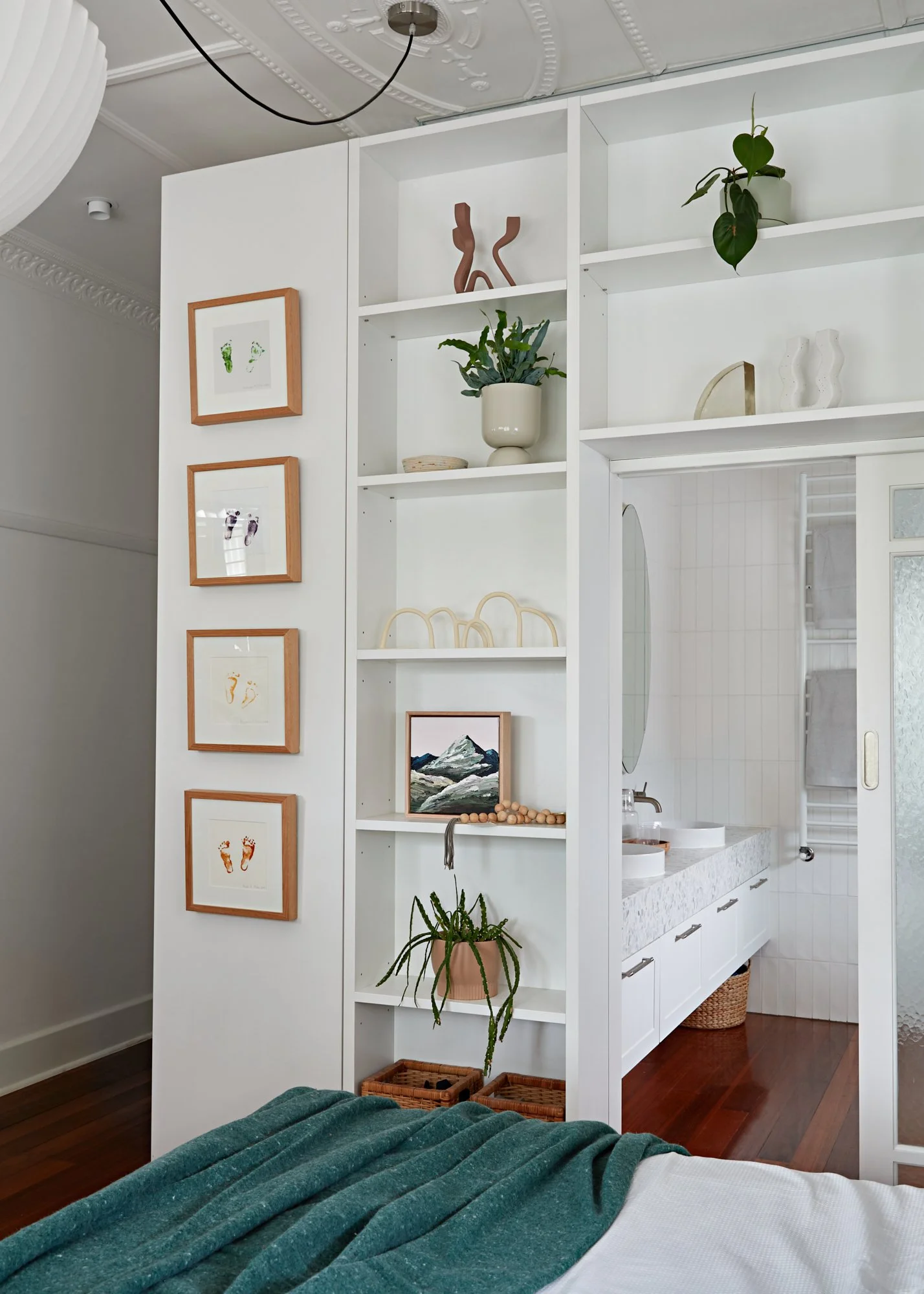 Built-in bedroom shelving and storage with a sliding door connecting to the ensuite at Adella Court, Elwood.