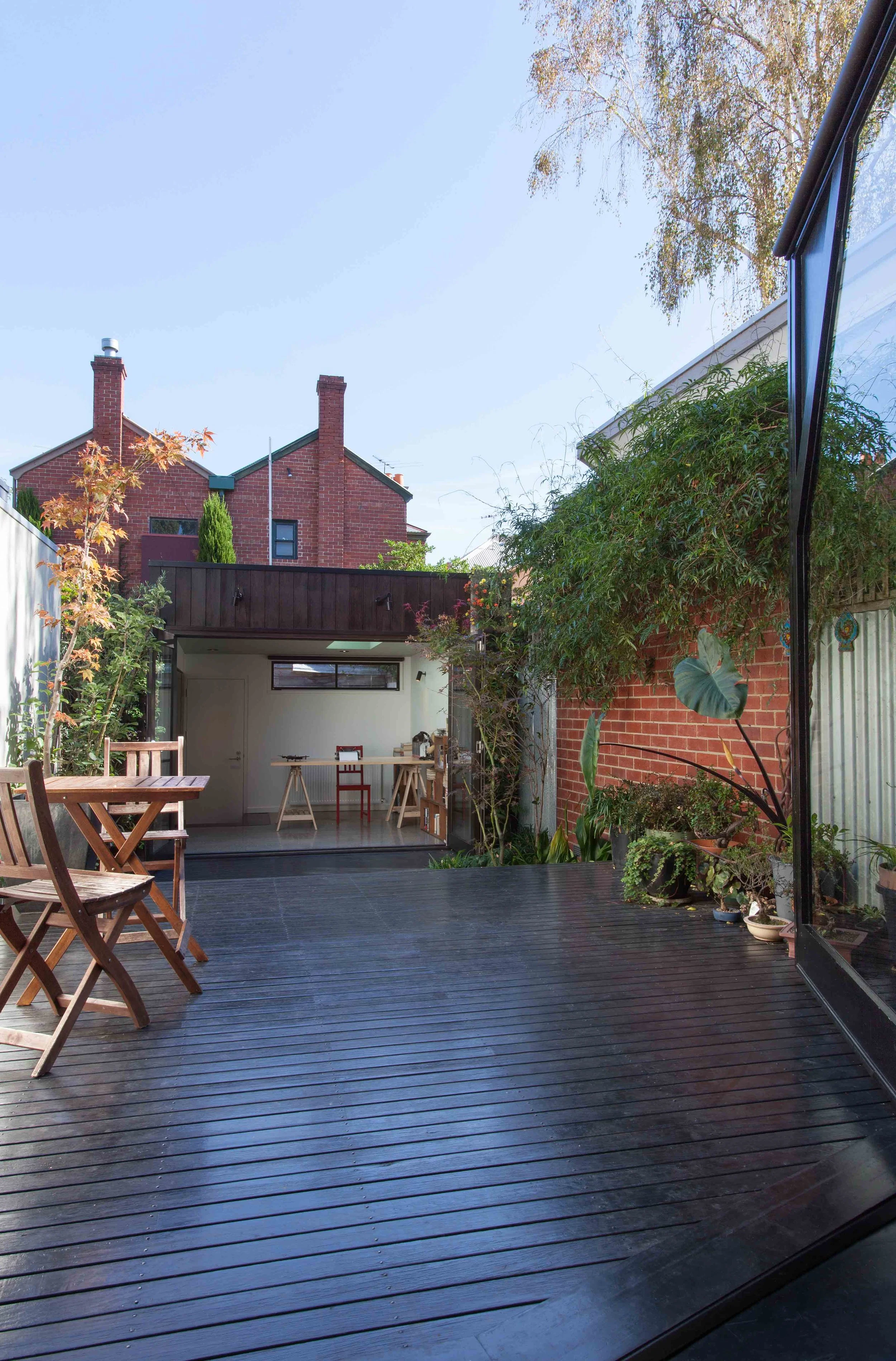 Long timber deck and landscaped courtyard connecting the main house with a compact garden studio.