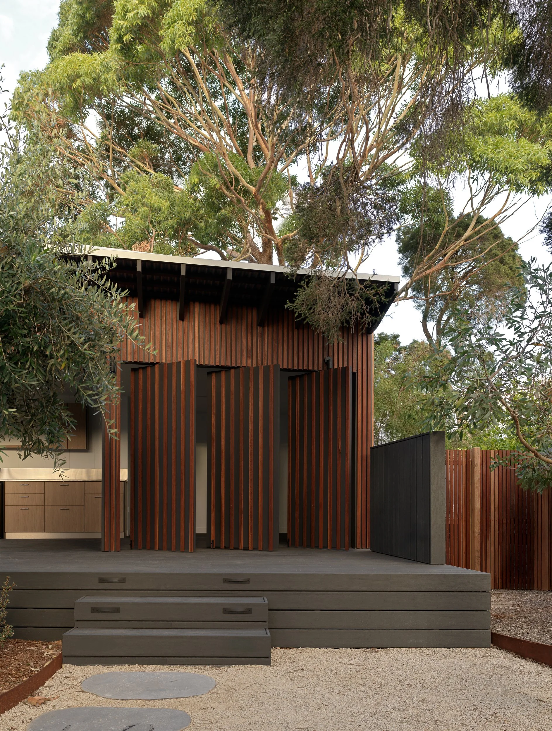 Cottesloe Retreat with timber screens opening onto the deck, surrounded by established trees and bushland.