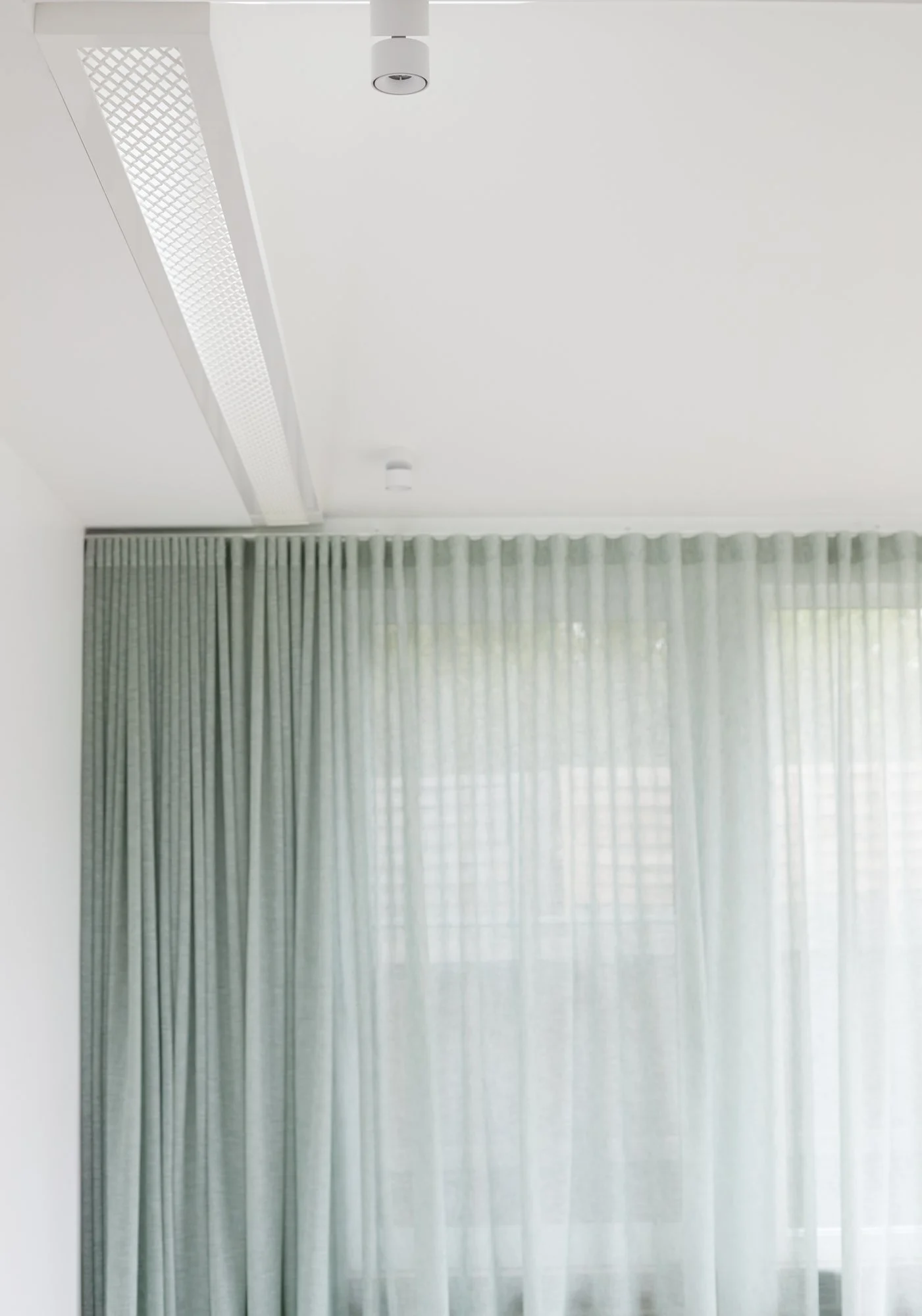 Detail of sheer green curtains and integrated ceiling shelving at Northcote Green House.