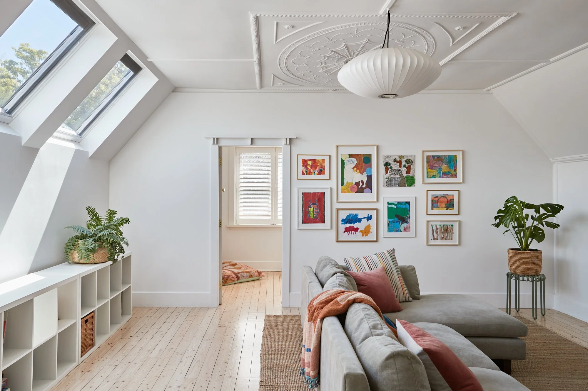 Upstairs living room with skylights, decorative ceiling detail, timber floors and gallery wall at Adella Court, Elwood.