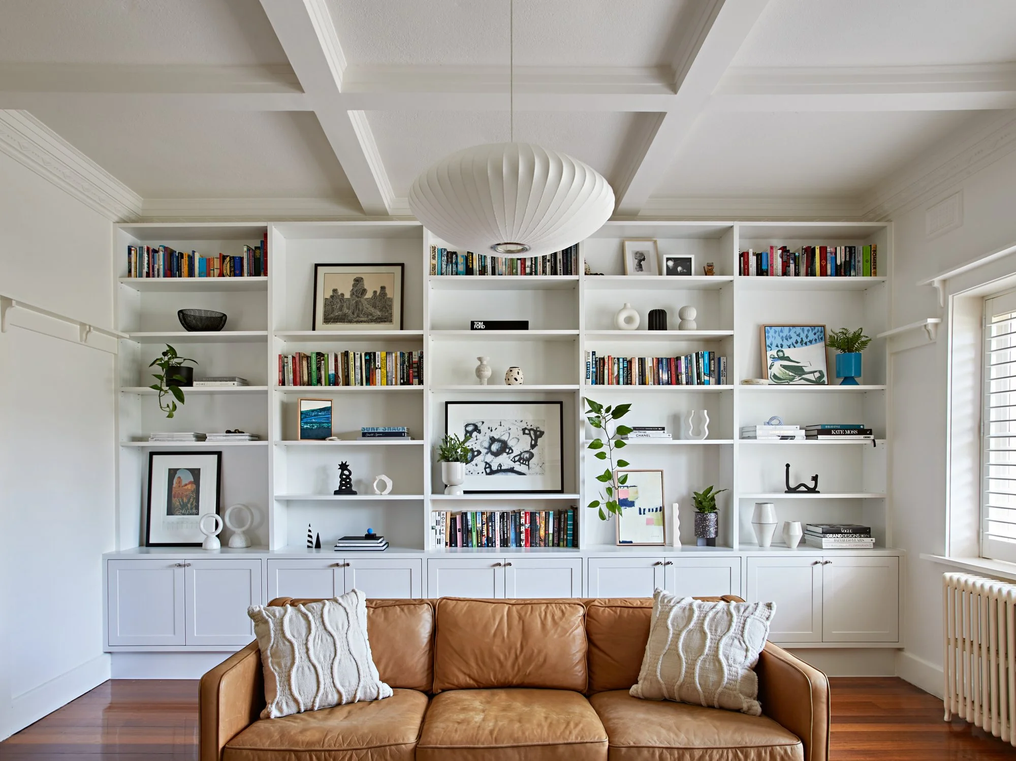 Living room at Adella Court, Elwood with full-height custom bookshelves, timber floors and original period details.