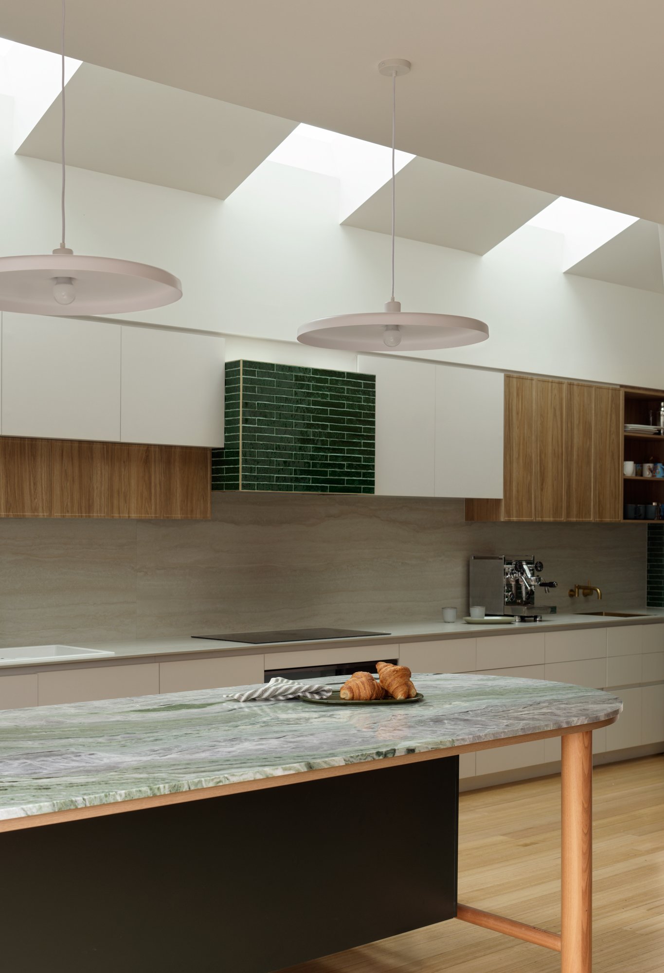 Northcote Extension kitchen with white and timber cabinetry, green tiled detailing, stone island and overhead skylights.