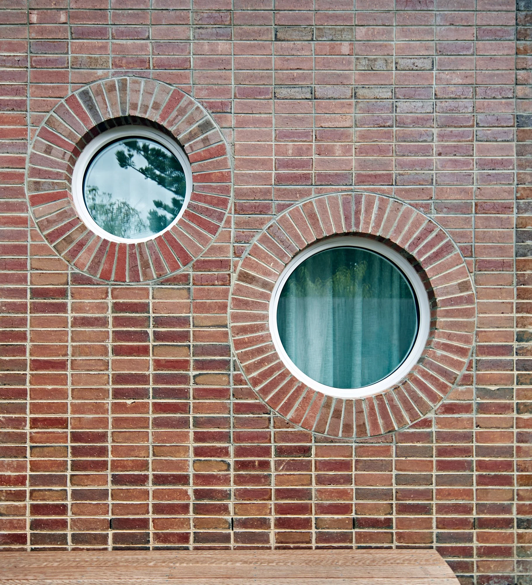 Two circular windows set into the red brick wall of Northcote Green House.