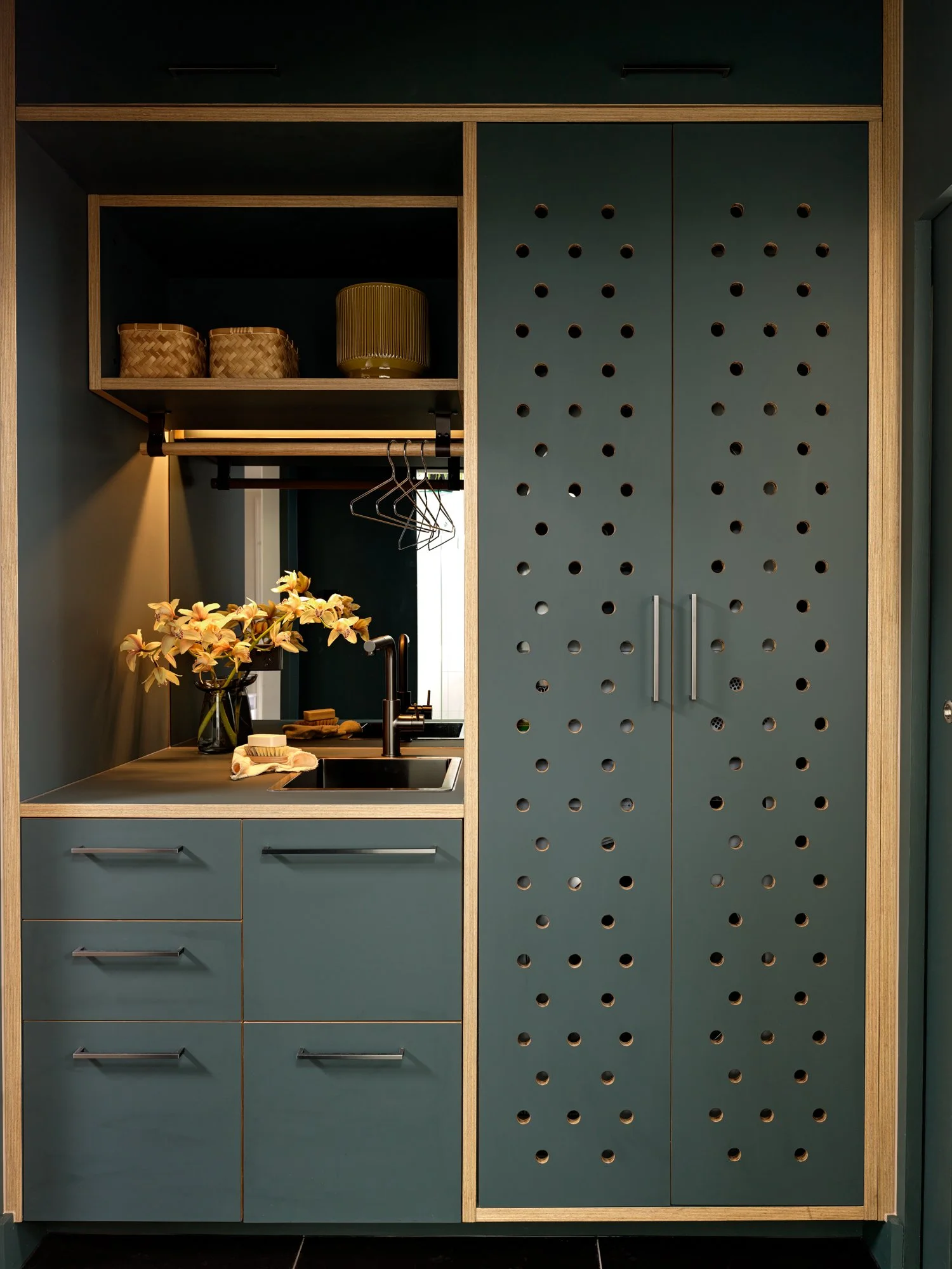 Brunswick Laundry with full-height perforated cabinetry concealing the laundry appliances beside the integrated sink.