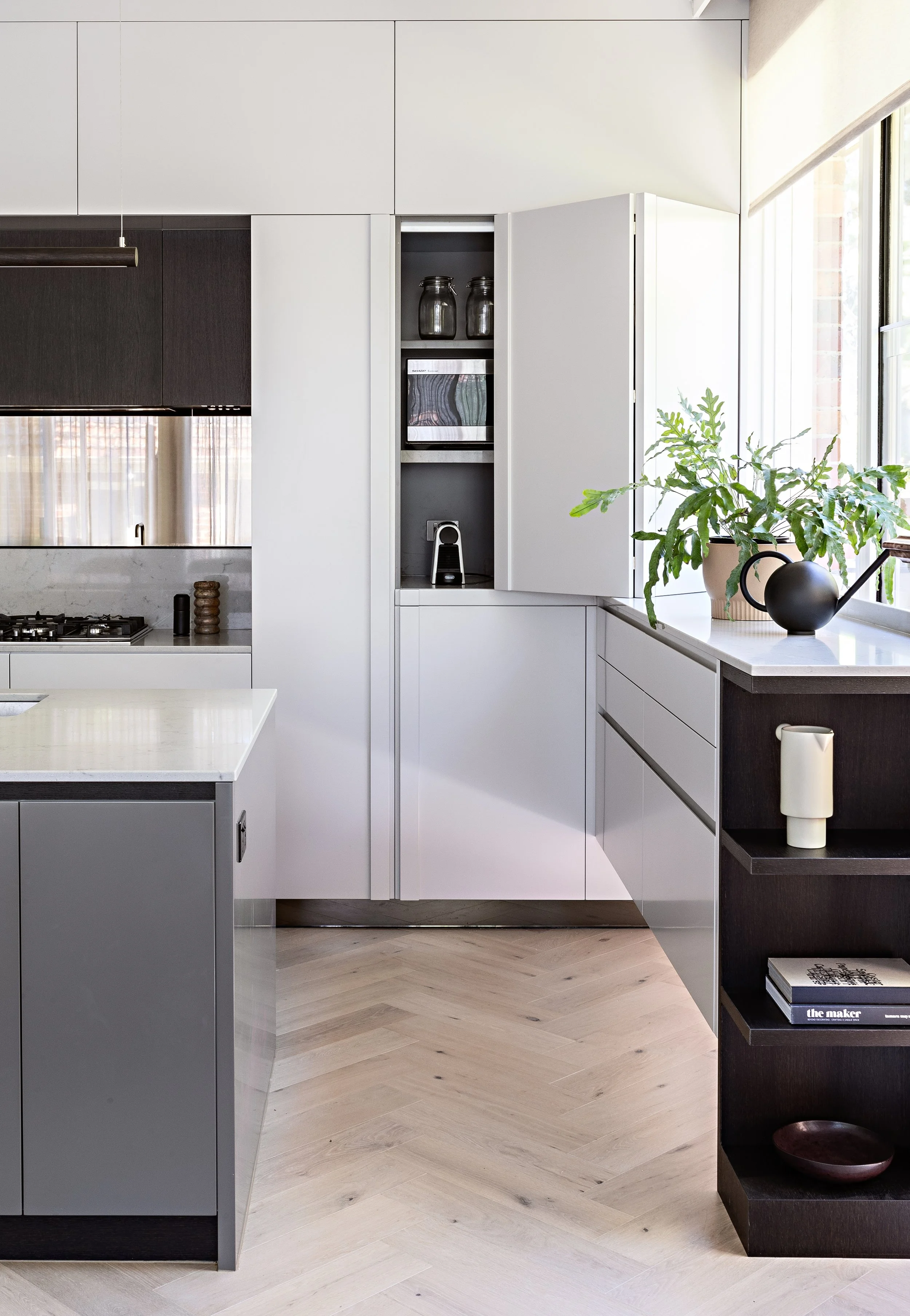 Integrated kitchen storage and cabinetry with concealed appliance station and open shelving at Brighton East House.