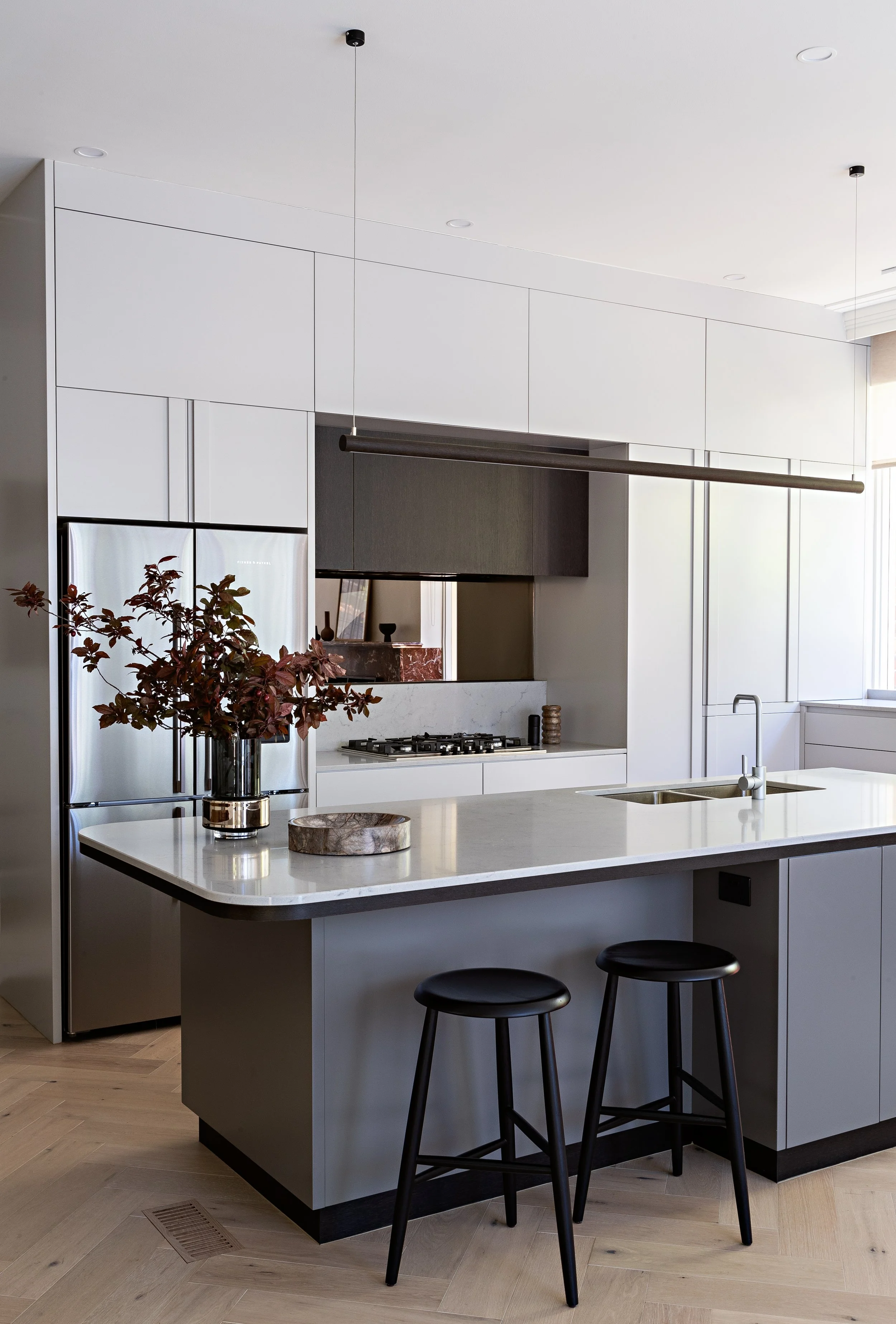 Contemporary kitchen with large island bench, integrated cabinetry and linear pendant light at Brighton East House.