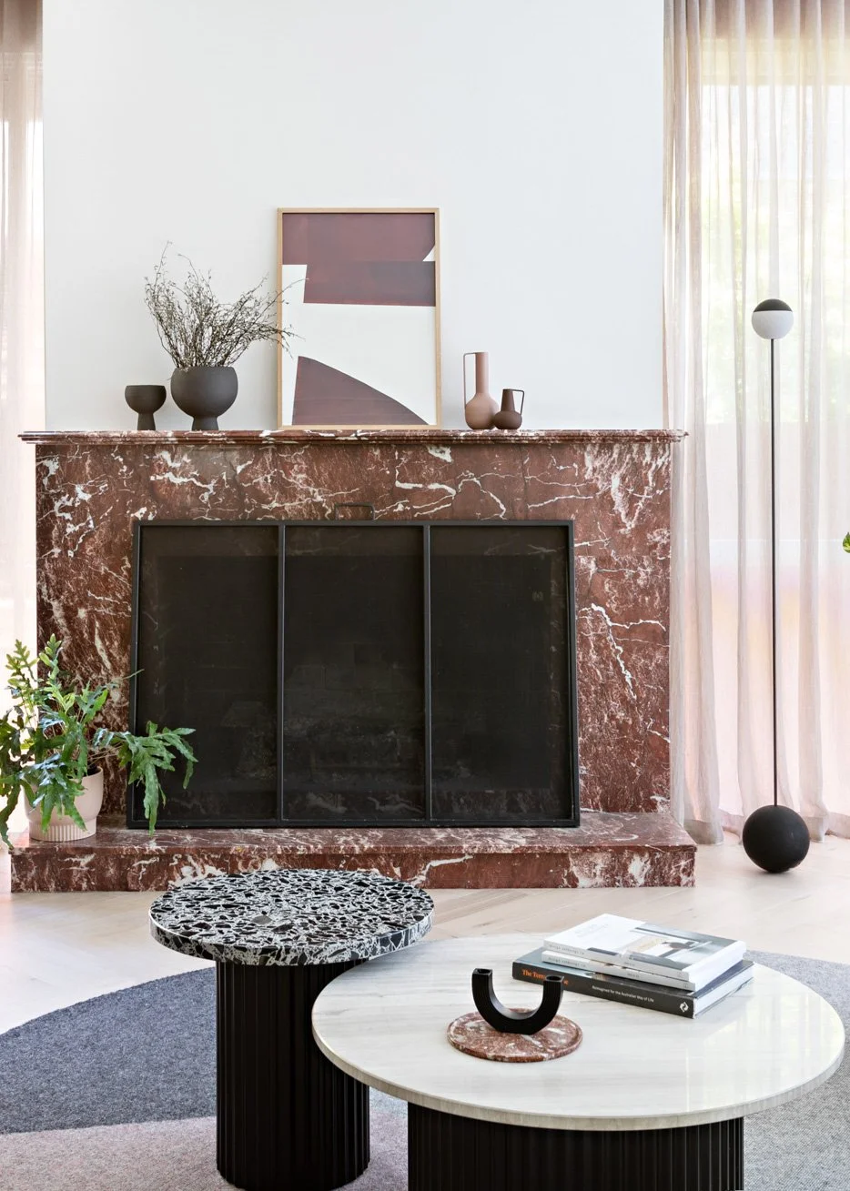 Red marble fireplace with black steel screen in the living room of Brighton East House.