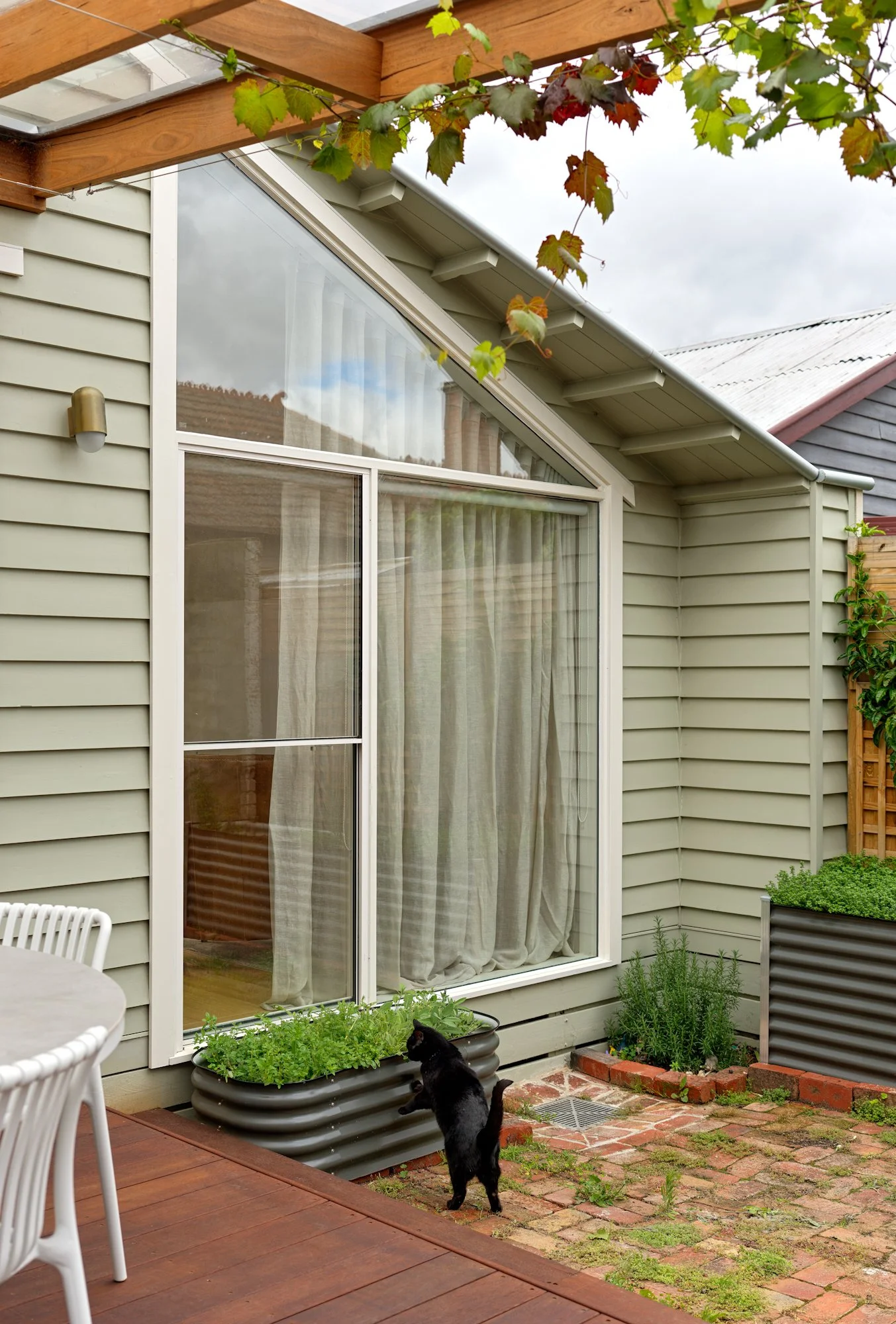 Northcote Extension viewed from the garden, showing the large windows, timber deck and connection between the kitchen and outdoor space.