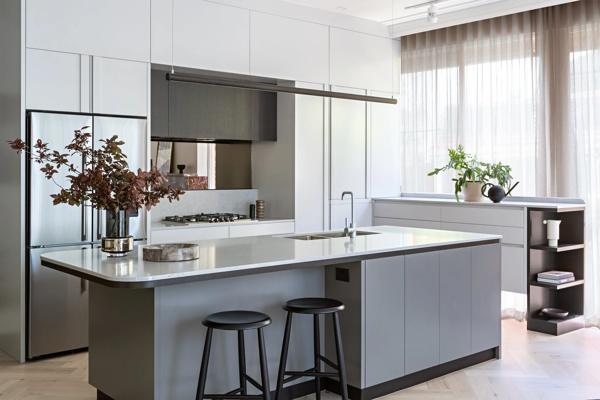 Brighton East House kitchen featuring a large island, streamlined cabinetry, integrated appliances and window-side storage.