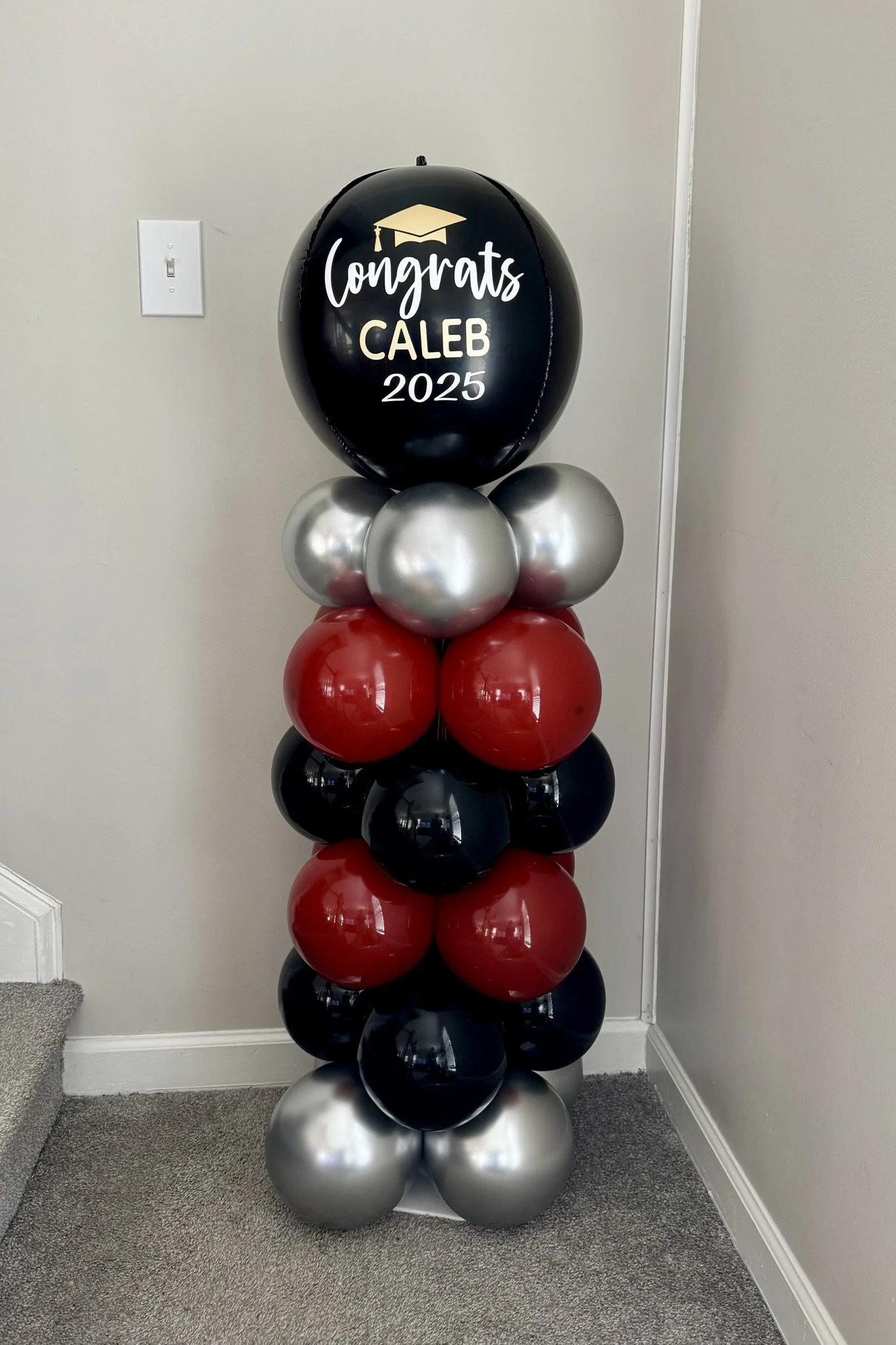 Graduation balloon column made of red black and silver balloons.