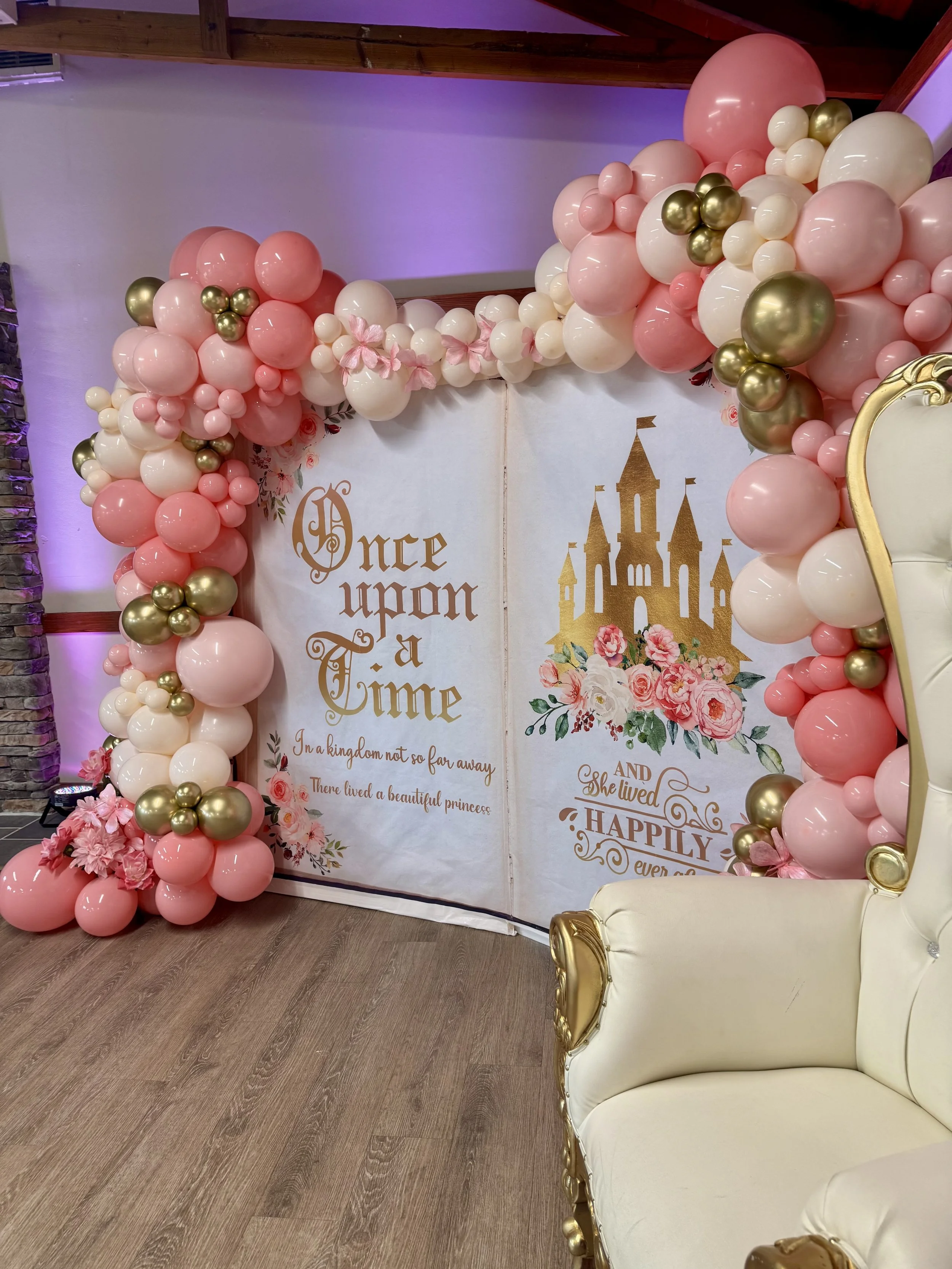 Whimsical fairytale balloon backdrop designed with blush pink, ivory, and metallic gold balloons accented by florals. Styled around a storybook backdrop that reads ‘Once Upon a Time’ and ‘Happily Ever After’, this balloon display is perfect for princ