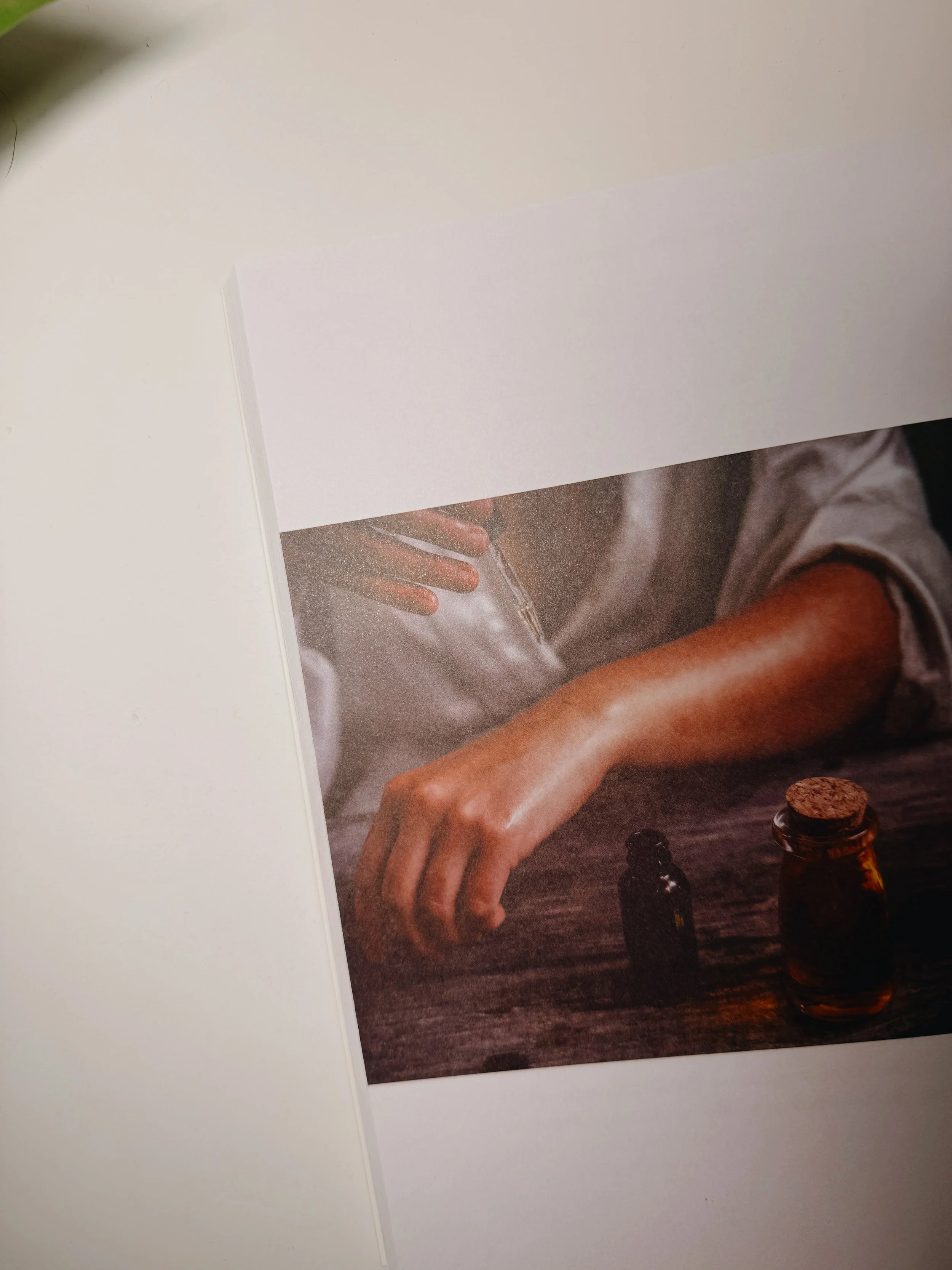 Close-up of a person holding a dropper above a wooden surface with two small bottles, one with a cork.