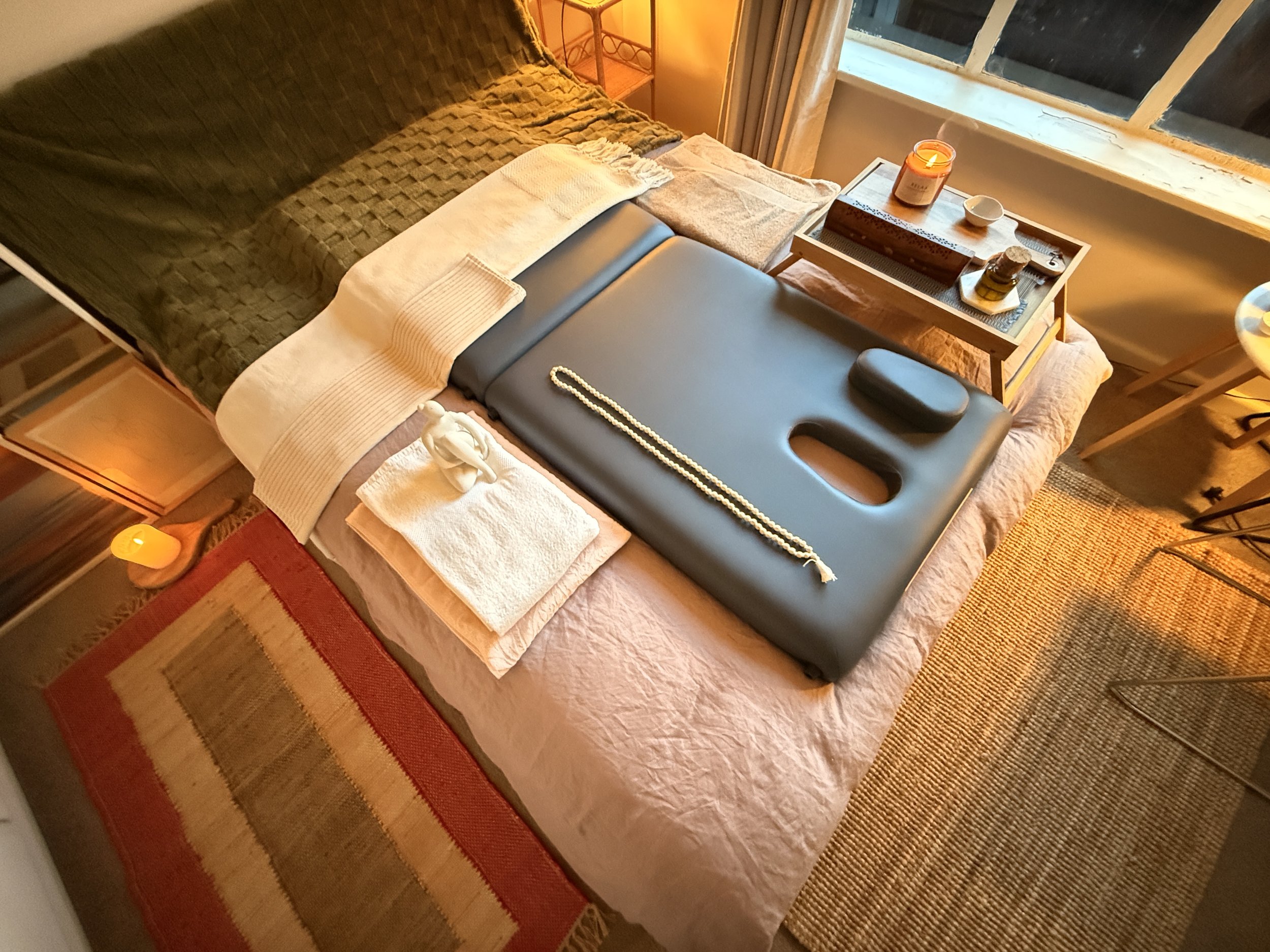 Massage table set up in a cozy room with blankets and candles