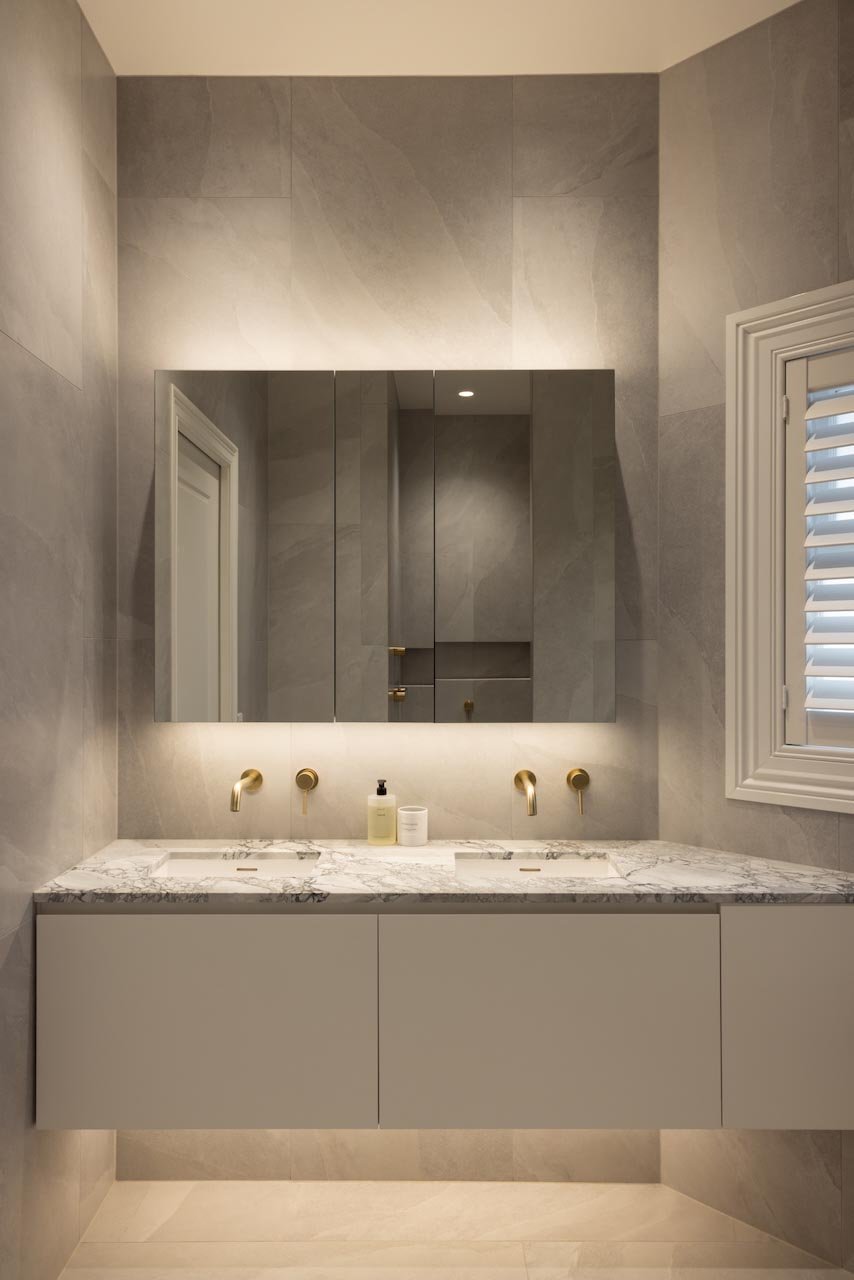 Double vanity with brass tapware, a back lit LED mirror cabinet.