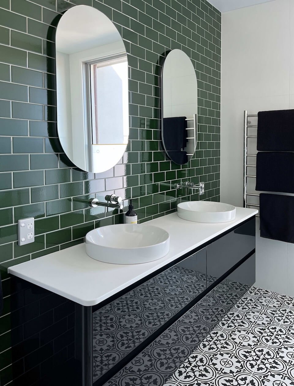 modern bathroom with green tiles on the wall and black and white tiles on the floor