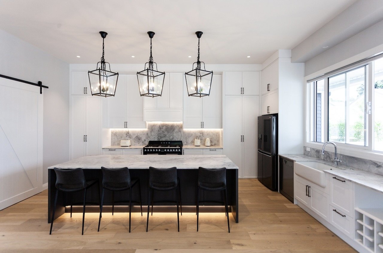 Traditional kitchen with white panelled doors and black island with marble bench